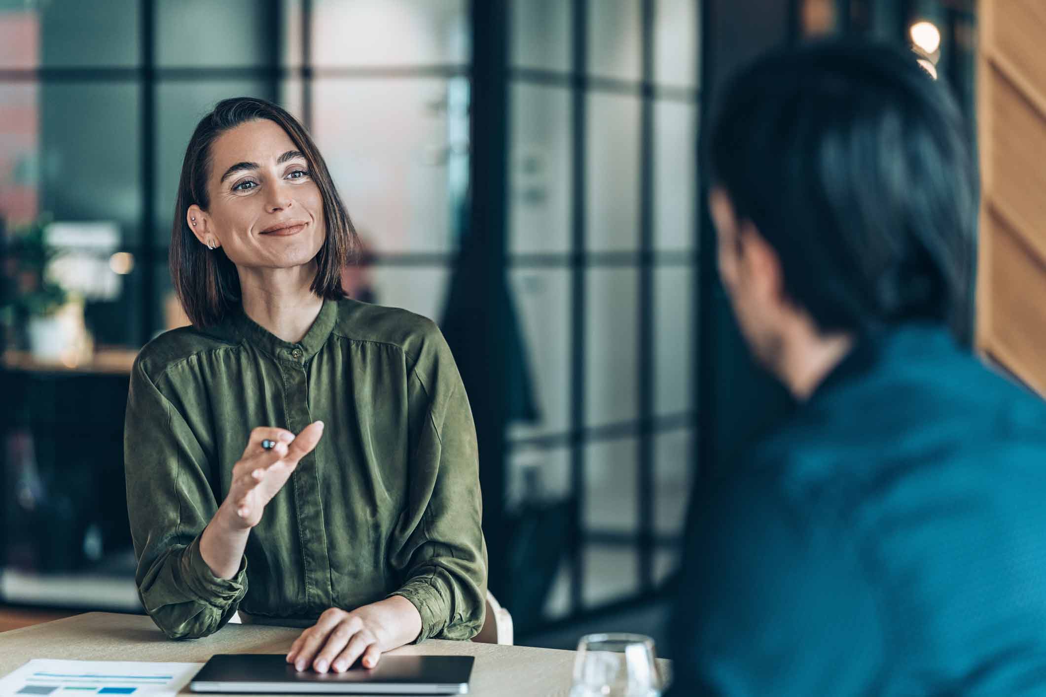 Woman smiling and discussing Document Management Execution with a colleague in an office.