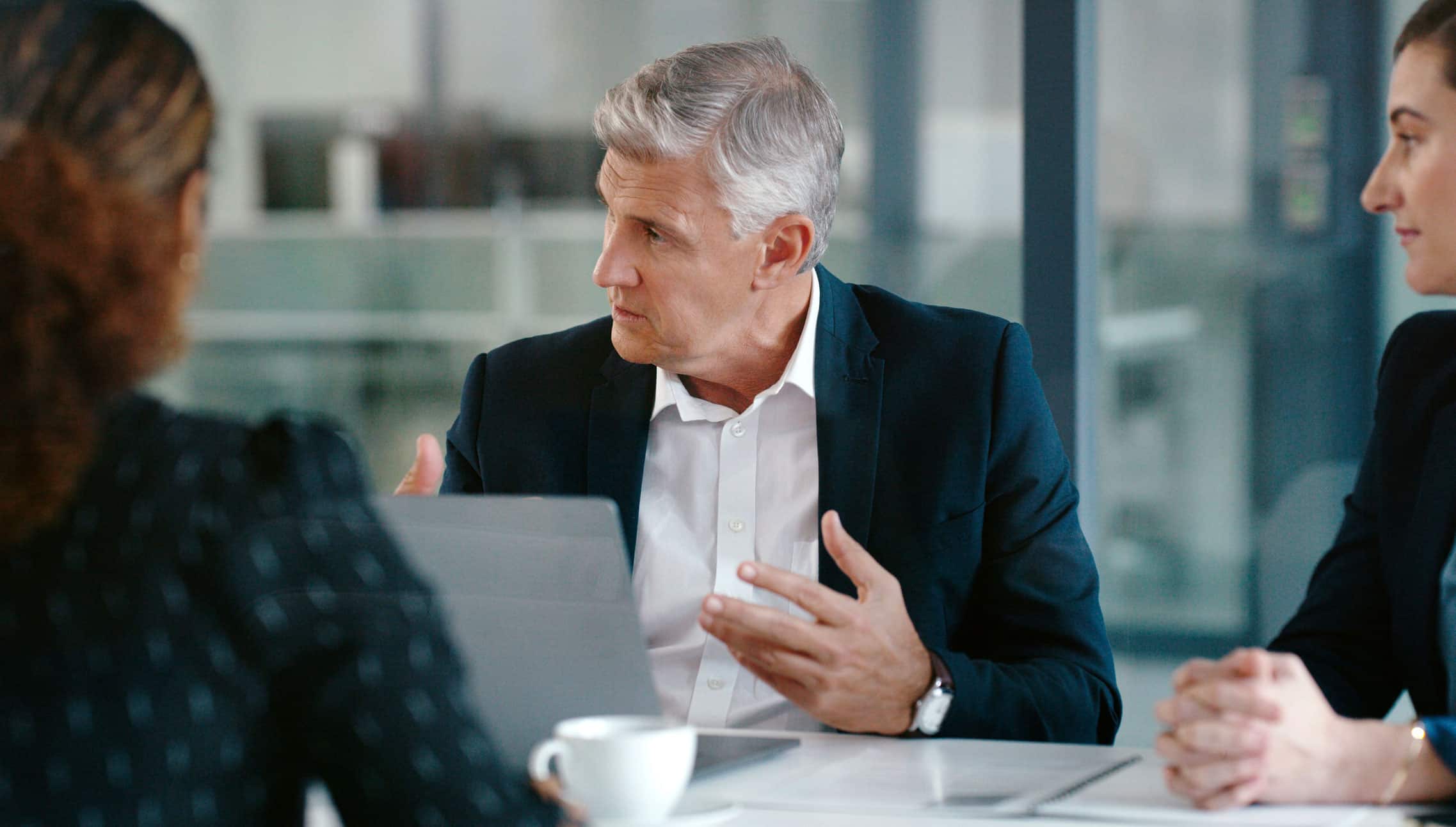 Man in suit discusses Data Governance Advisory with colleagues at a modern office table.