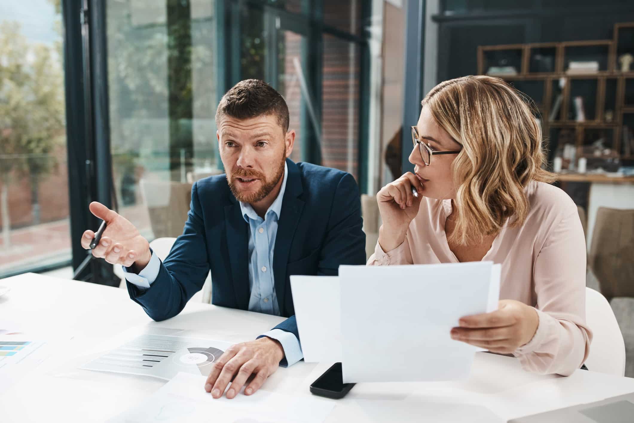 Two people in business attire discuss eDiscovery Project Management at a modern office desk.