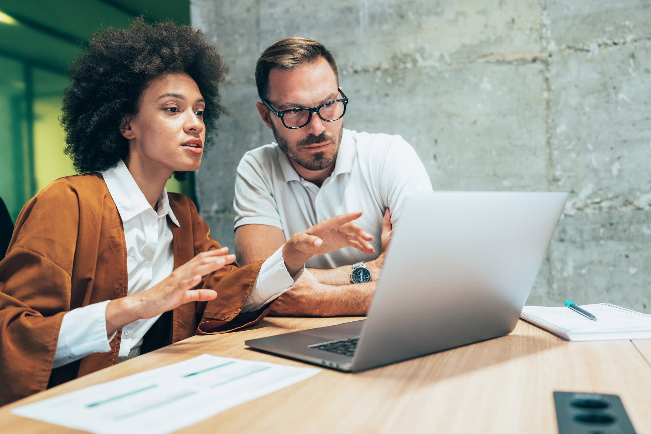 Two colleagues discuss Law Firms resource optimization at a laptop in a modern office setting.