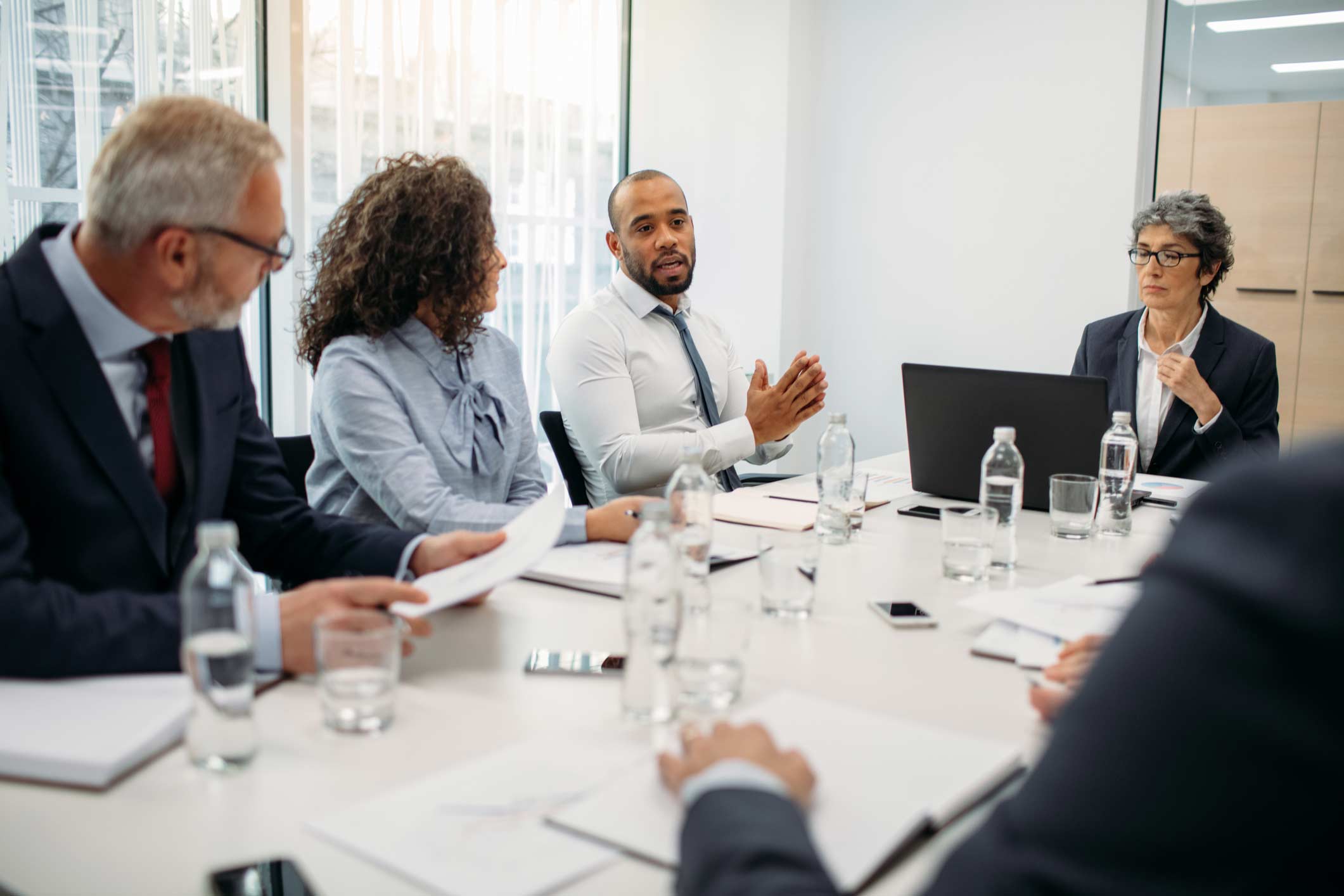 Five people in business attire discuss Advanced Analytics Consulting Services at conference table.