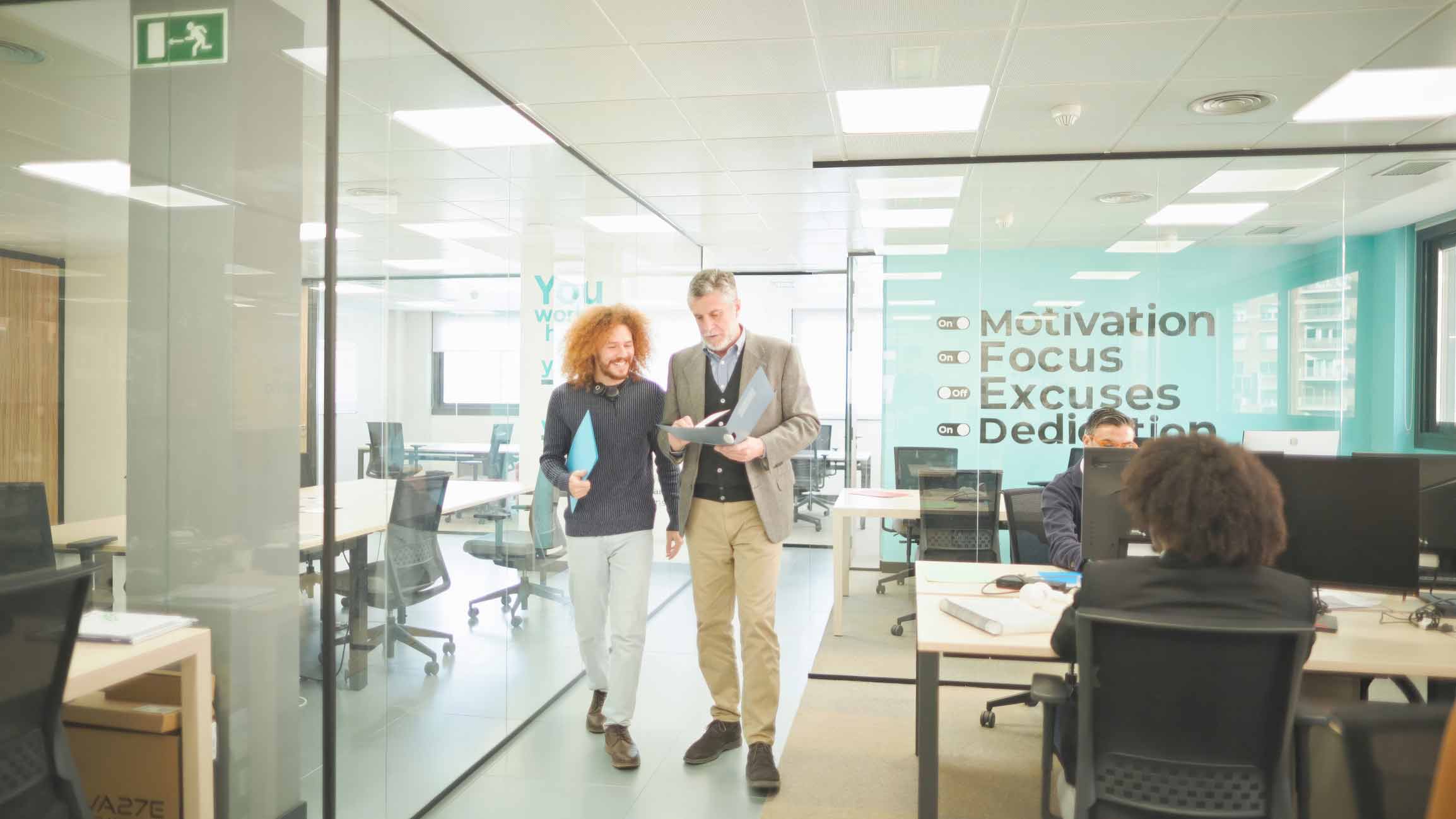 Two men discuss Document Management Governance & Policy in a modern office with glass walls.