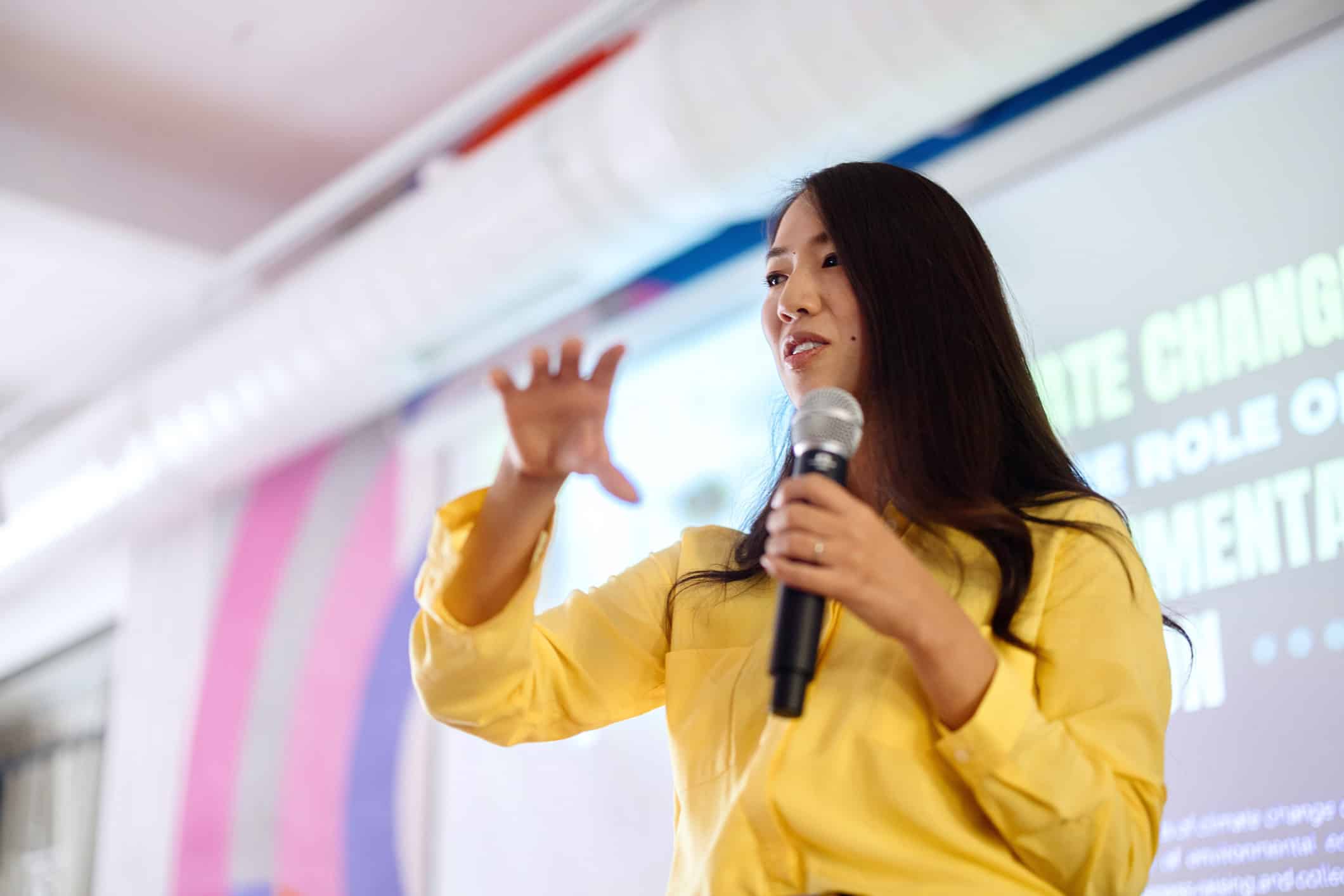 Woman in yellow shirt speaks on law firm strategic planning consultants during a presentation.