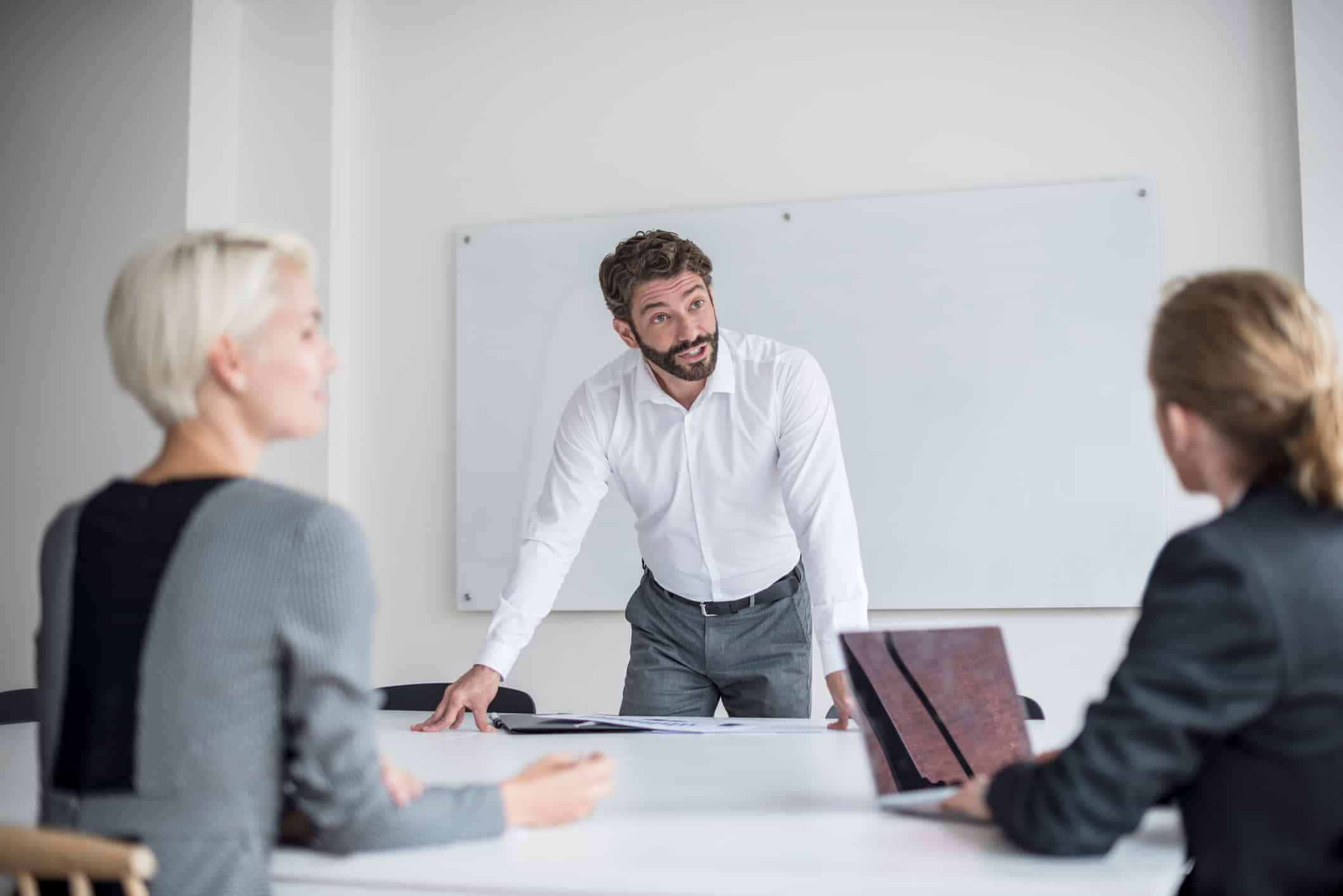 Man discussing organizational strategy consulting services with two colleagues at a conference table