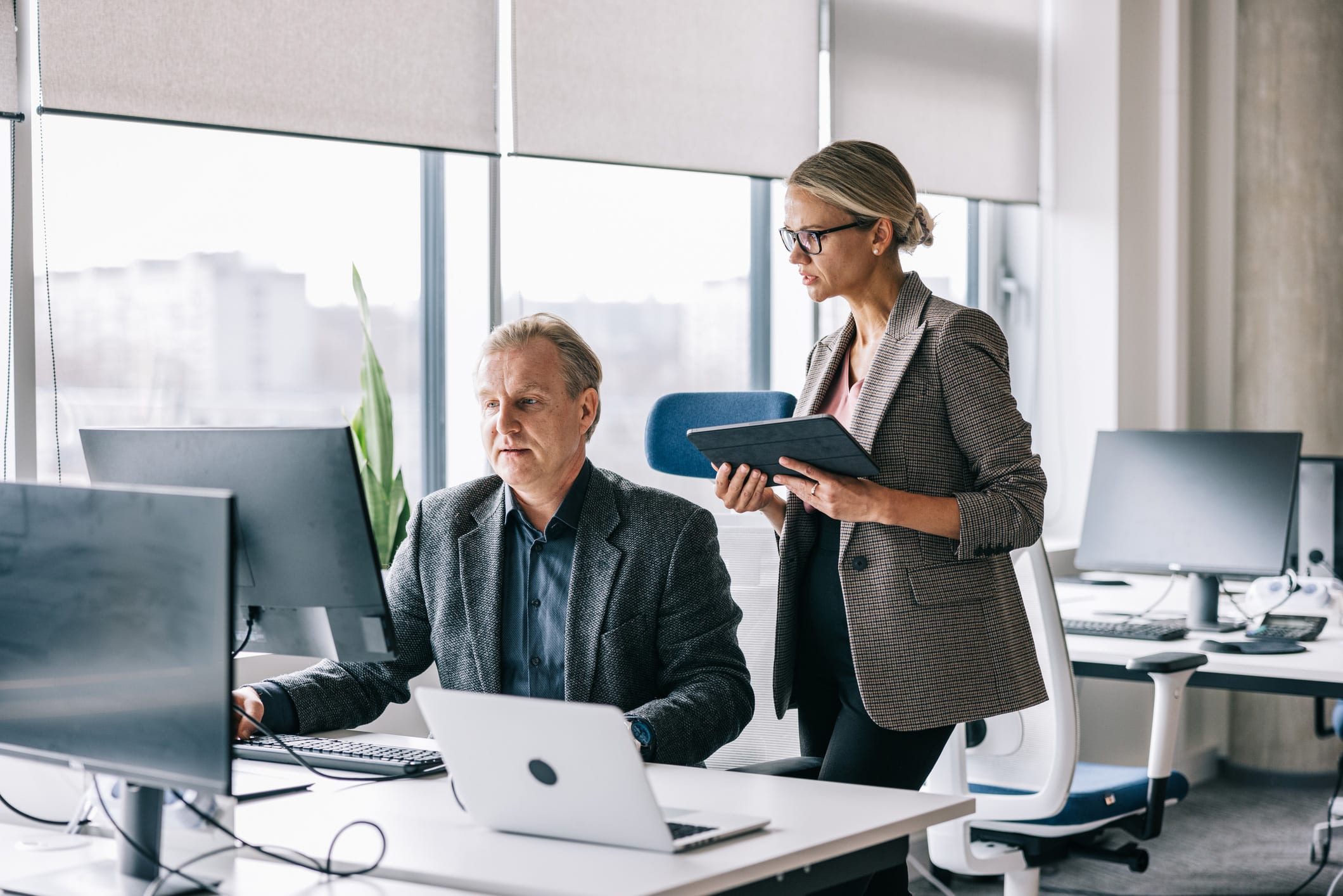 Two colleagues at computers in a modern eDiscovery Data Management Consulting Firm office.
