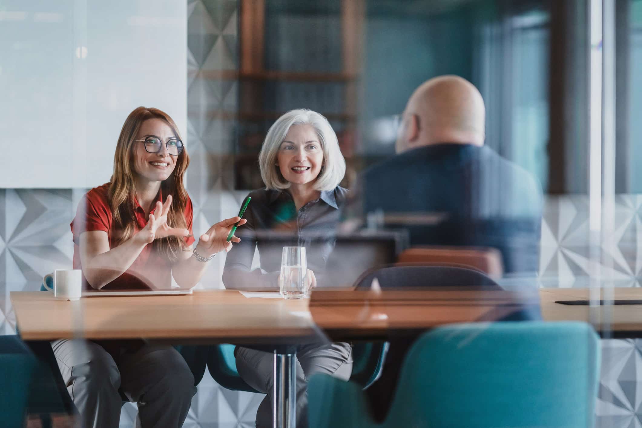Two women interview a man about Corporate Tax Incentive Optimization at a modern office table.