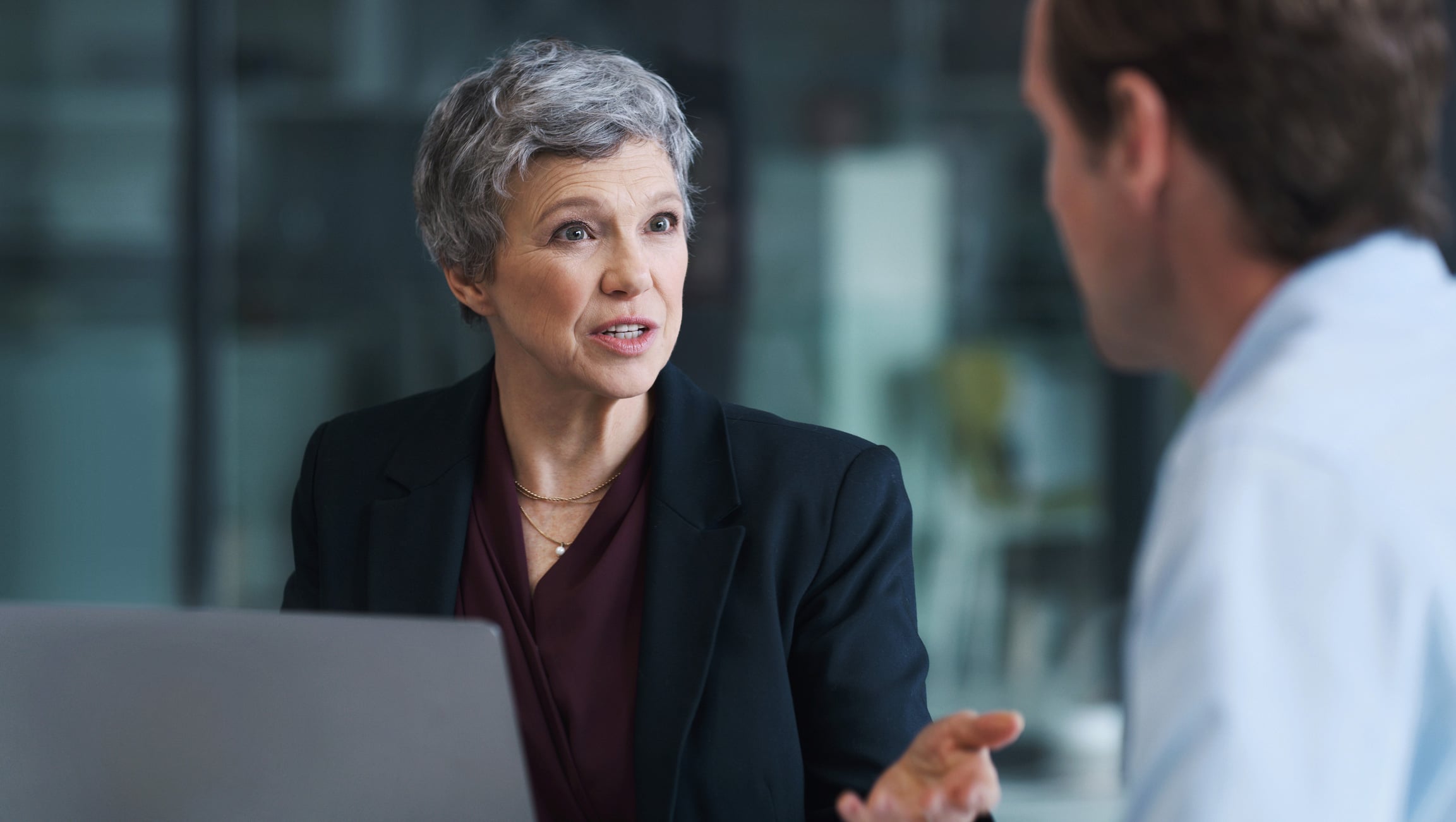 Older woman in a suit advises on law firm client retention strategy in an office setting.