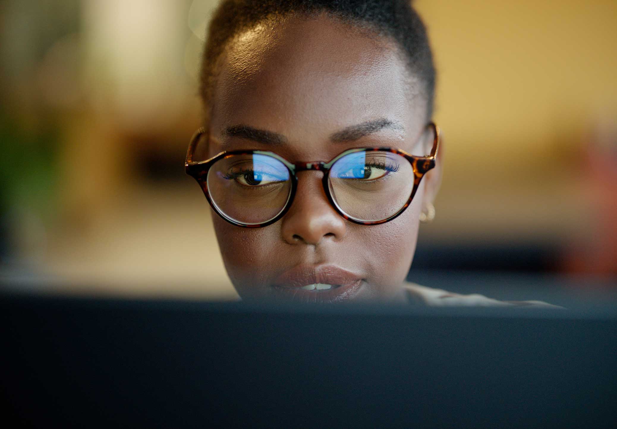 Woman with glasses focused on a computer screen, working at CAL Consulting.
