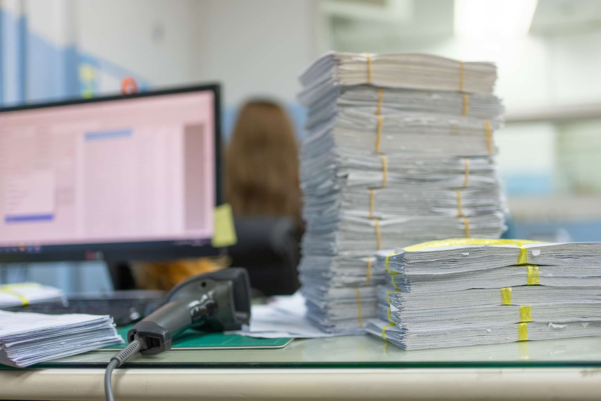 Stacks of documents on a desk, with eDiscovery Data Management Consultants at work nearby.