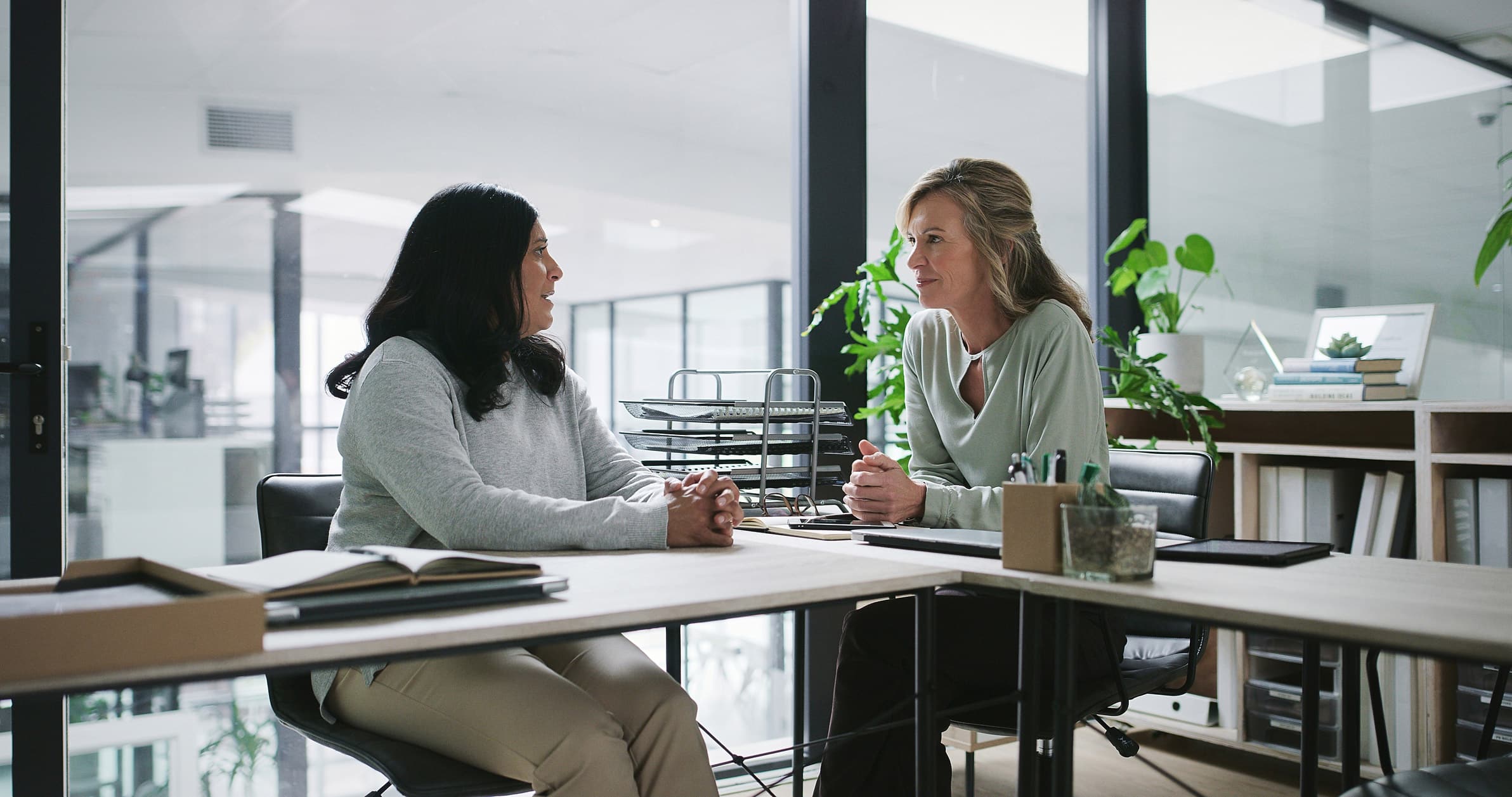Two women discuss Law Firm BPM Consulting Services in a modern office setting.