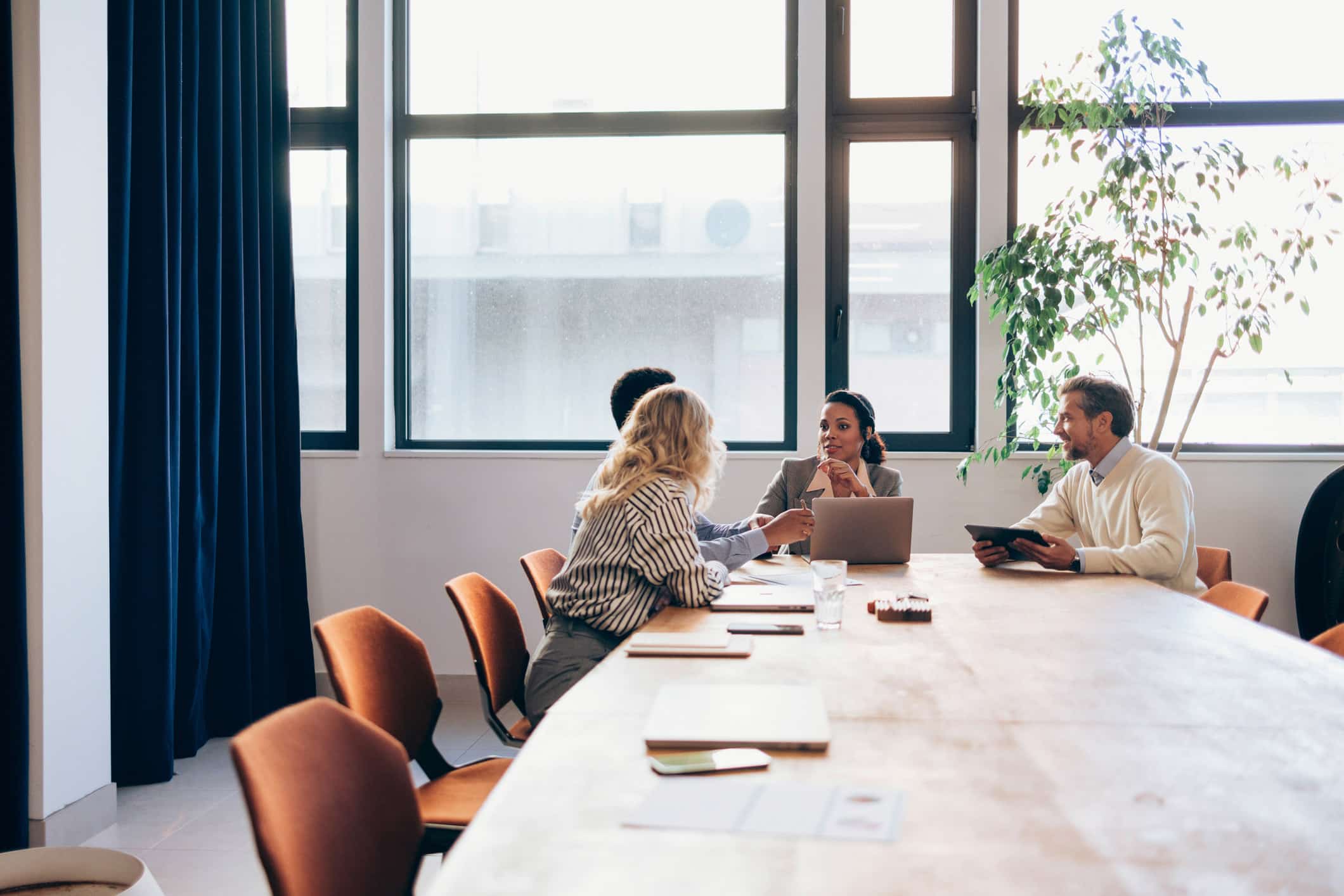 Four people sit at a conference table as Law Firms Resource Optimization Consultants meet.