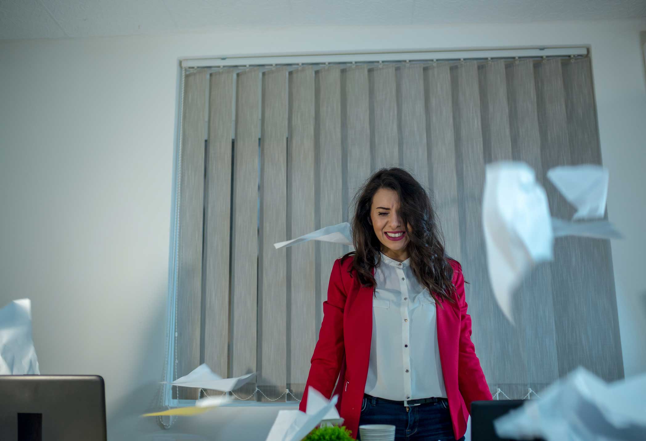 Woman in red blazer stands as papers for eDiscovery Artificial Intelligence Consultants fly at work.