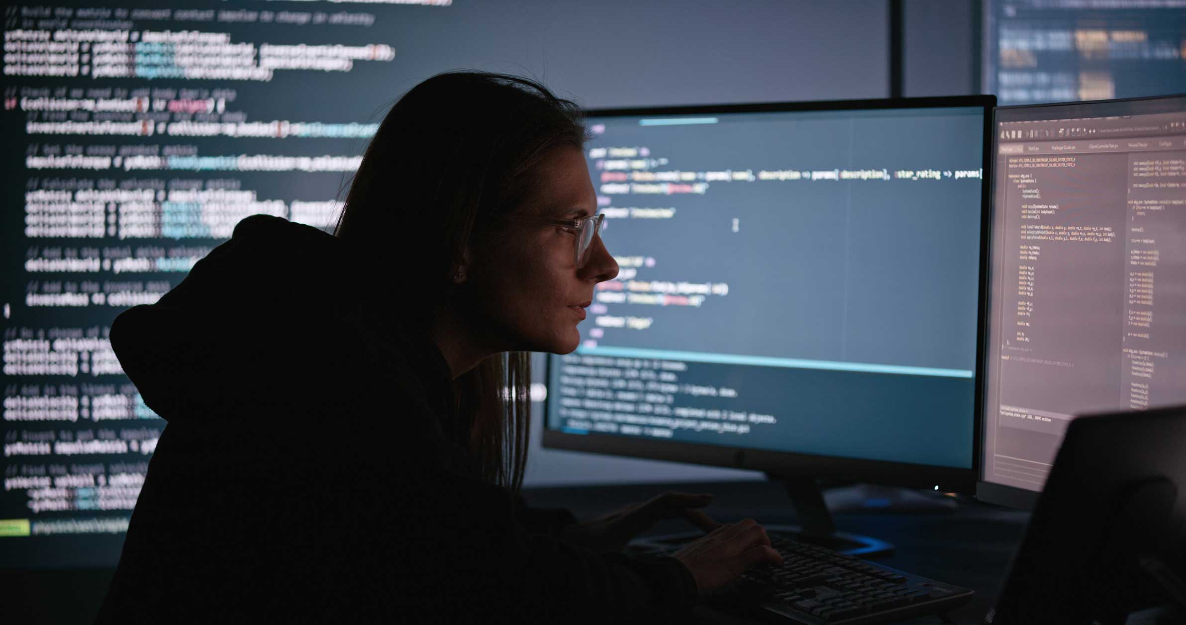 Person working at a computer desk for an identity access management consulting firm in a dark room.