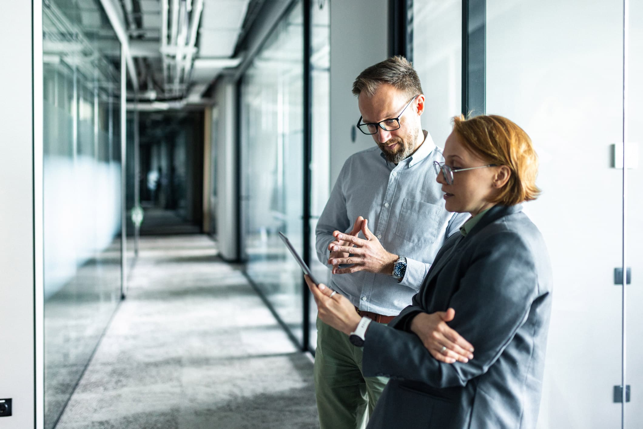 Law Firm Operations Consultants discuss strategies on a tablet in a modern office hallway.