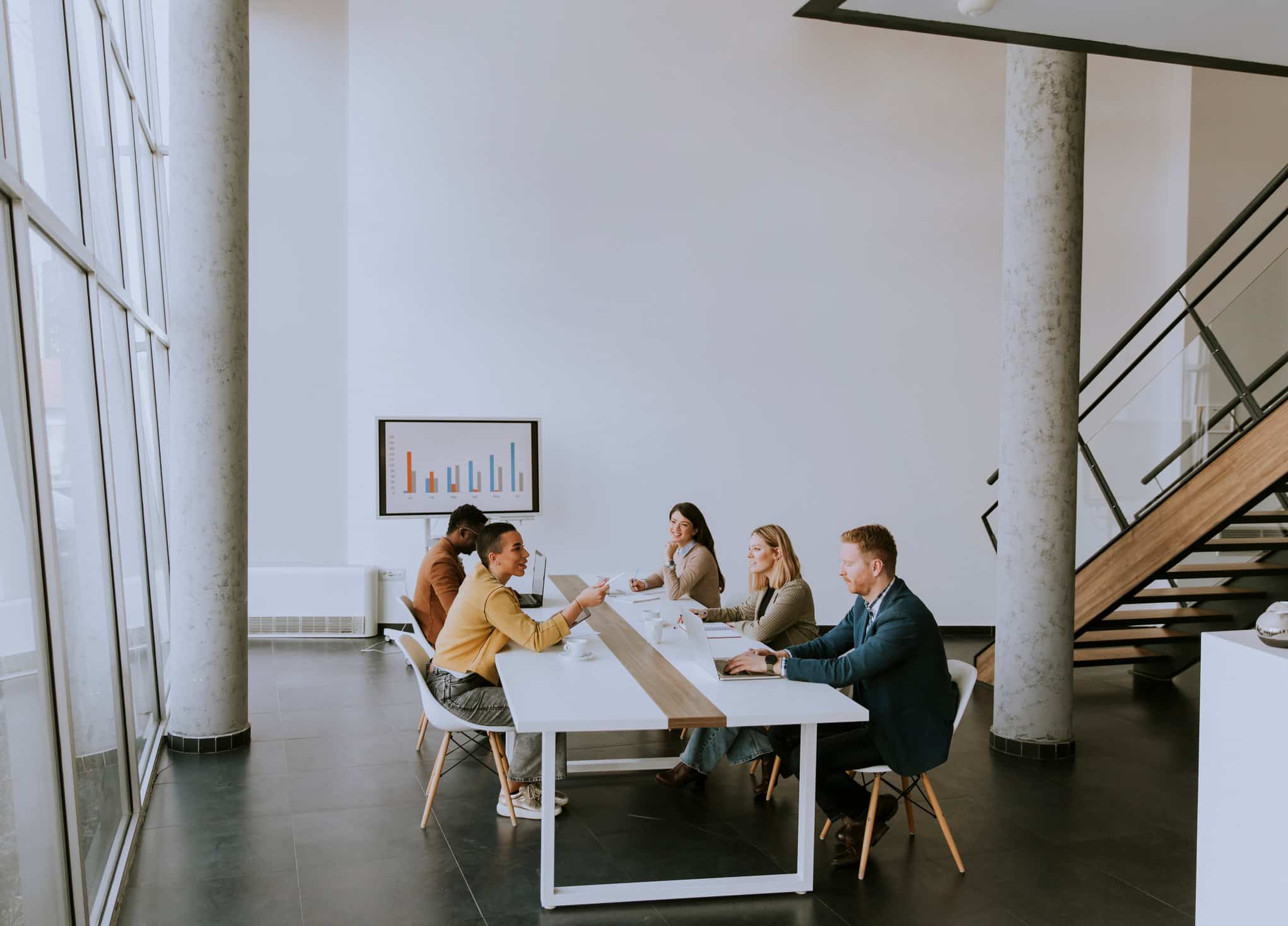 Six people sit at a long table in a modern office for a change management advisory meeting.