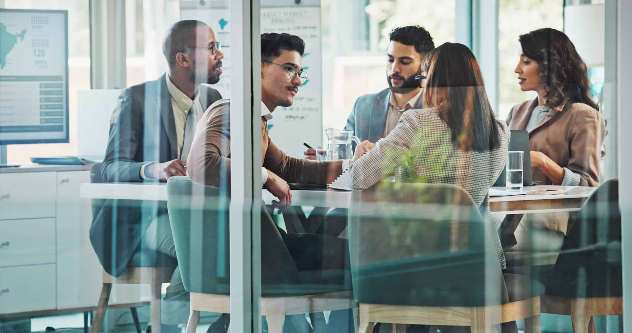Five people sit around a table in a modern office for a Practice Mix Optimization meeting.