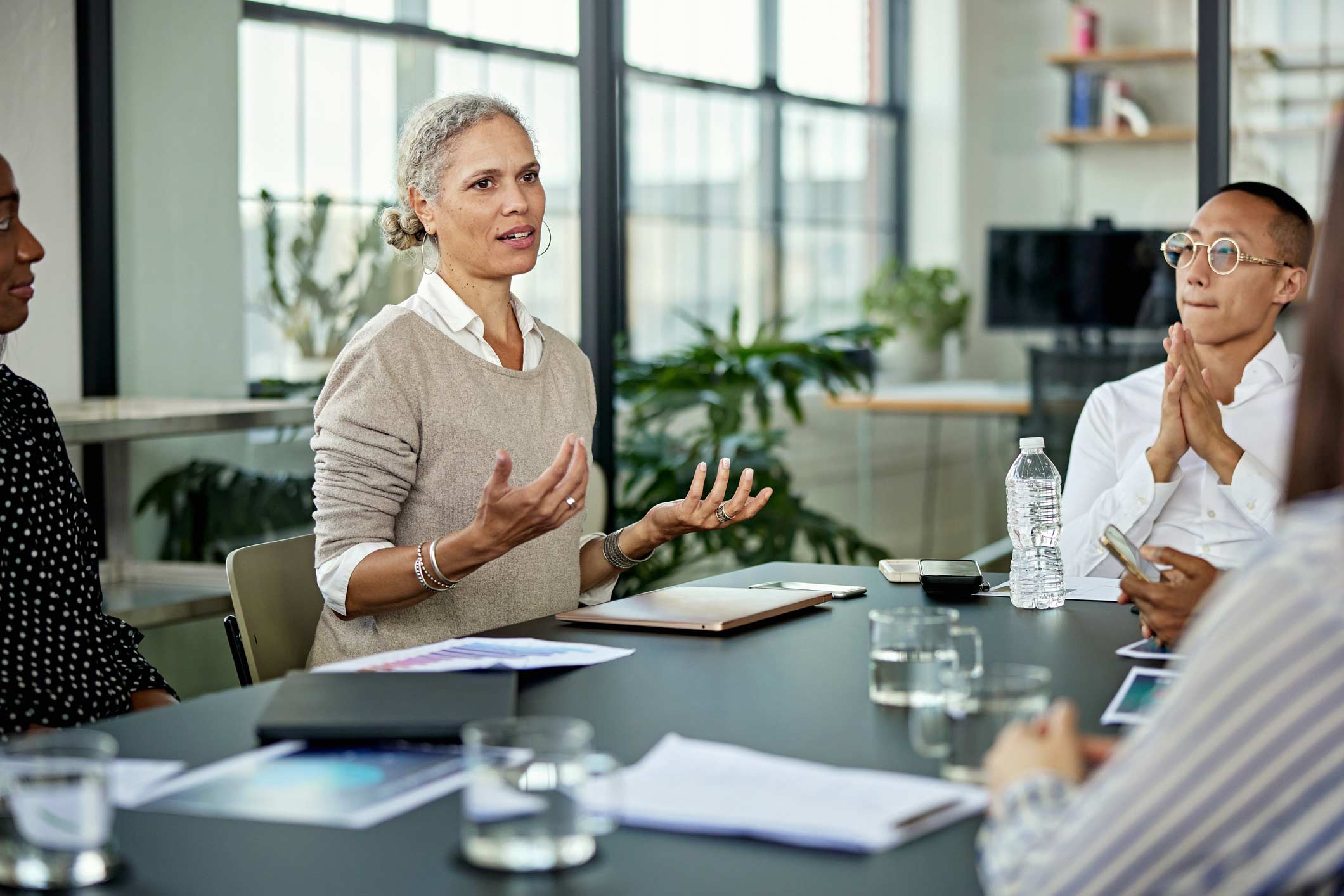 Older woman speaking in a meeting with Advanced Analytics Consultants in an office.