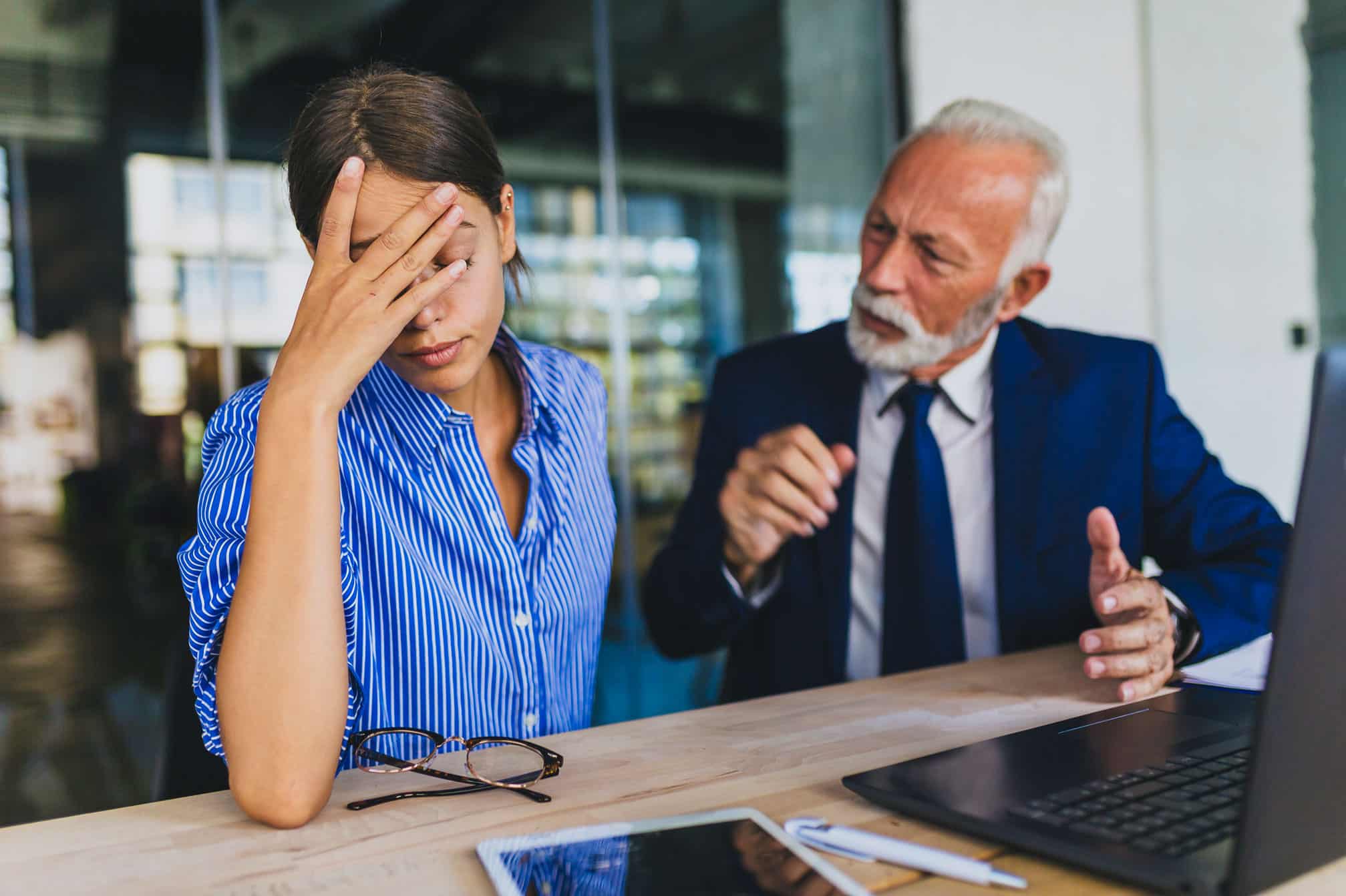 Young woman looks stressed as older man talks—consider employee wellness consulting services.