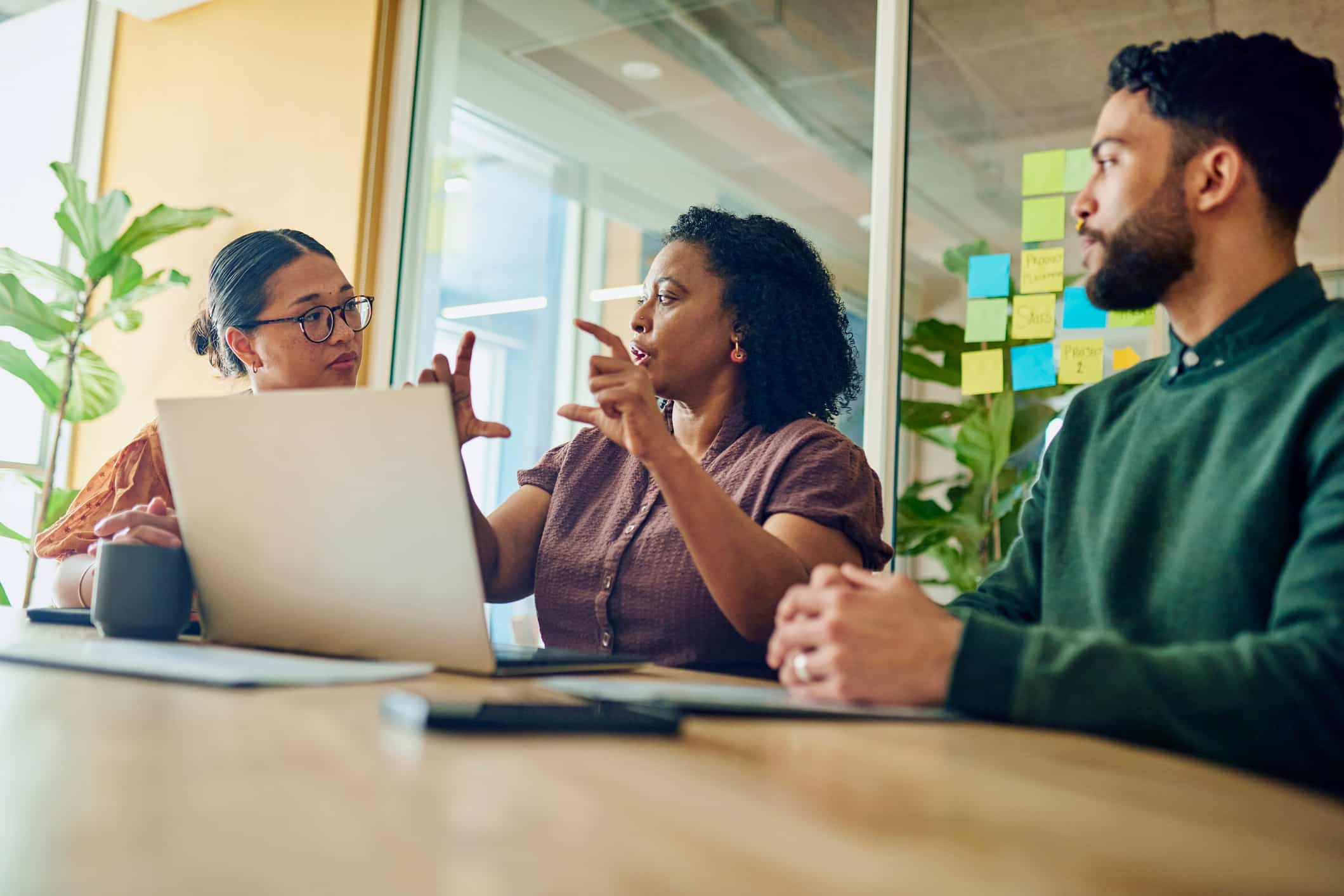 Three people discuss Technology-Assisted Review Advisory Services at a table with a laptop.
