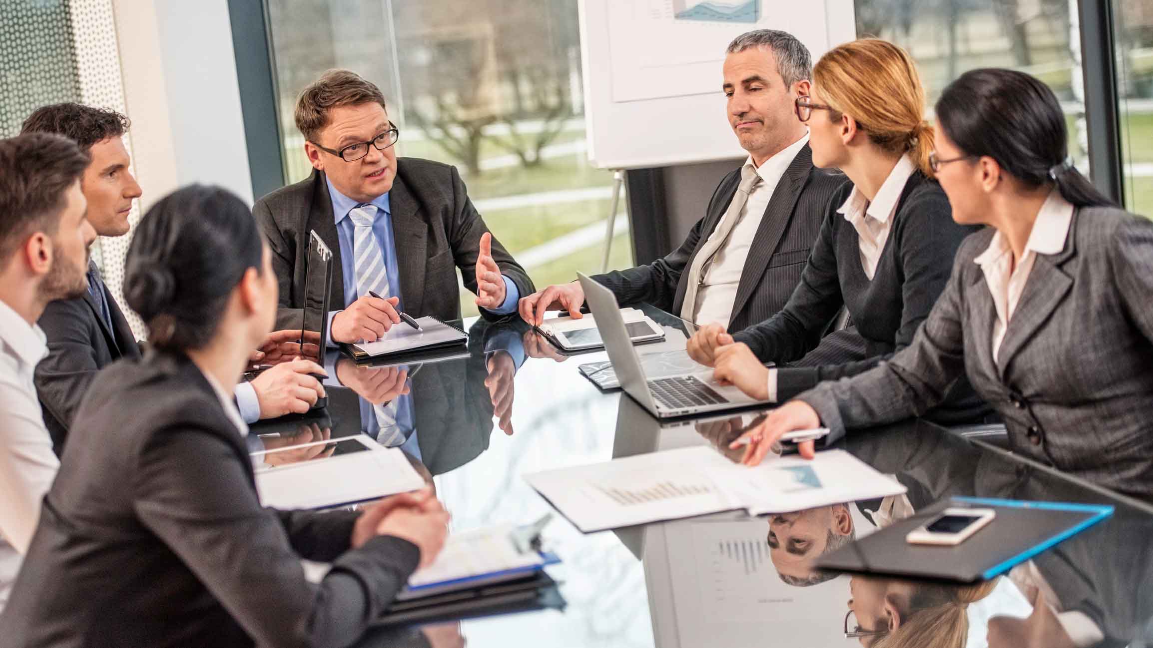 Businesspeople meet with cyber incident response consultants in a modern glass office.