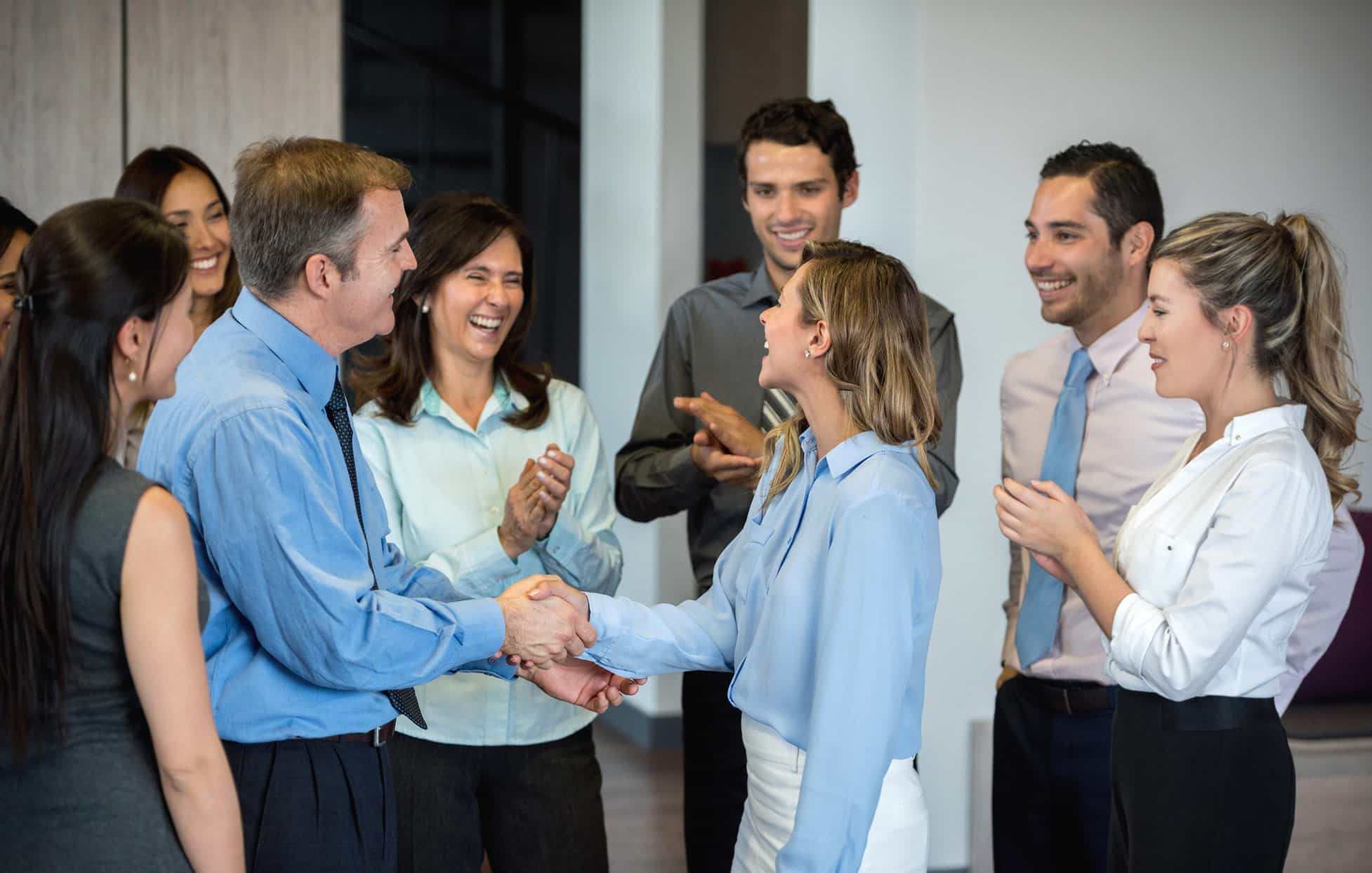 Coworkers celebrate workforce development design as two people shake hands in the office.