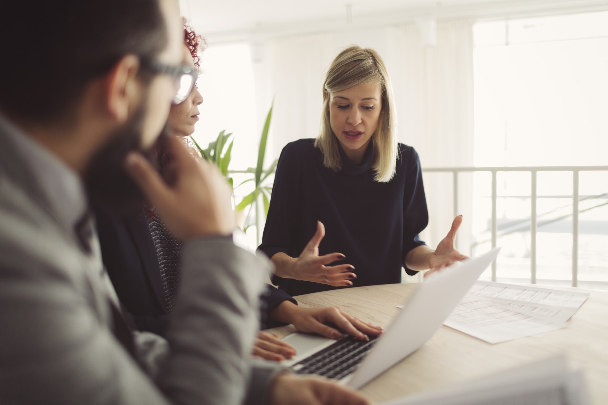 Three people discussing eDiscovery Data Management Consulting with a laptop and documents.