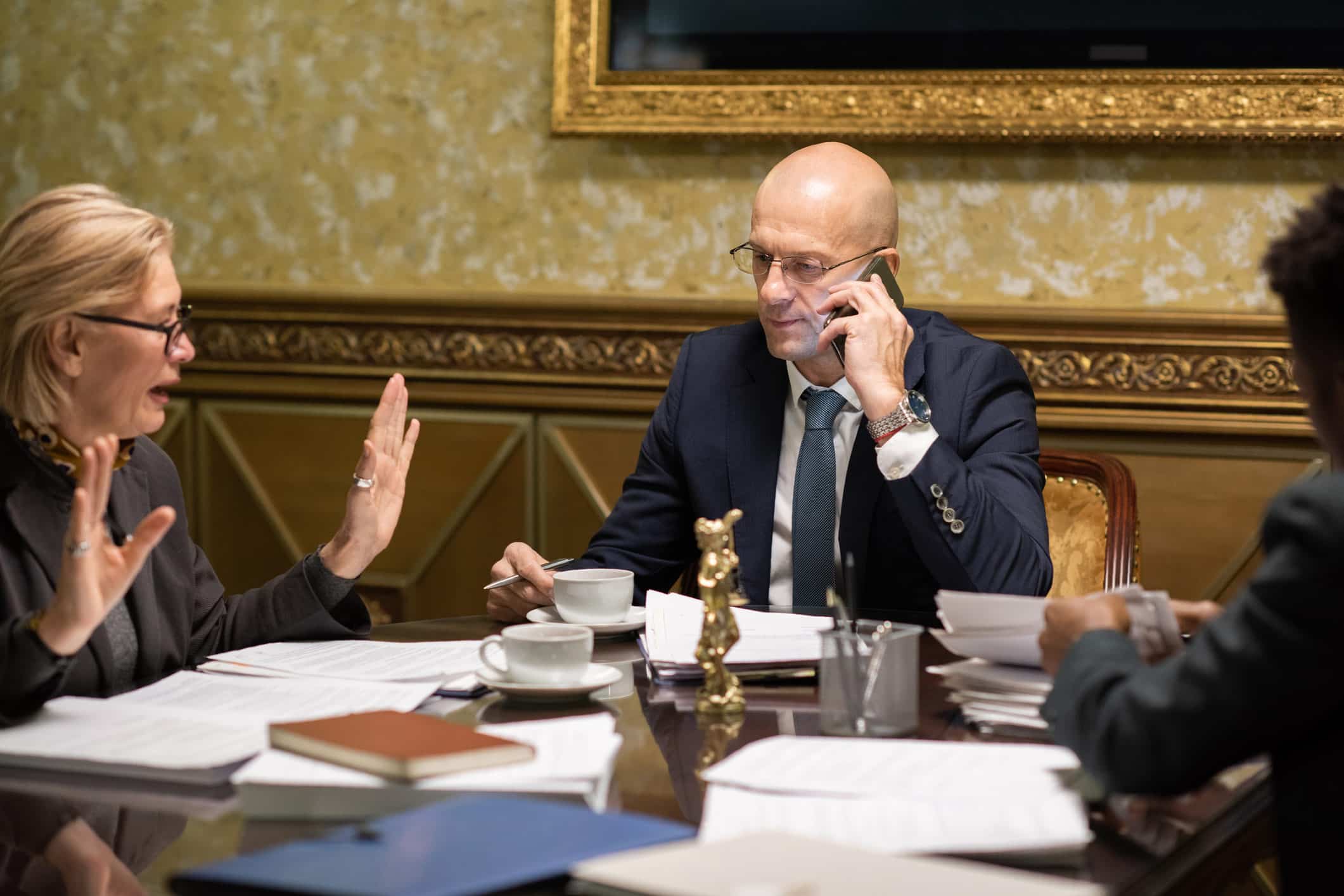 Three people in business attire at a Real-Time Analytics Consulting Firm, one on the phone.
