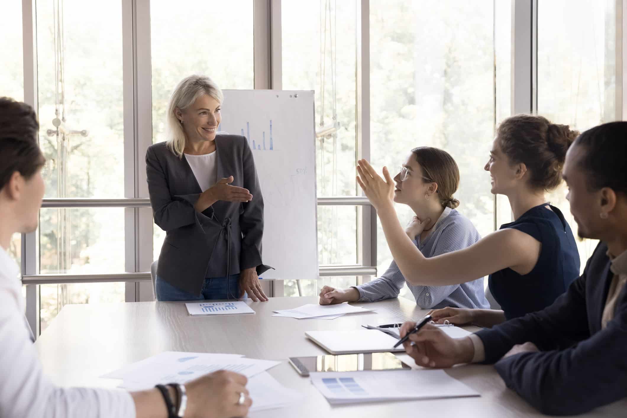 Woman leading a business meeting on NLP Model Development with four colleagues in a bright office.