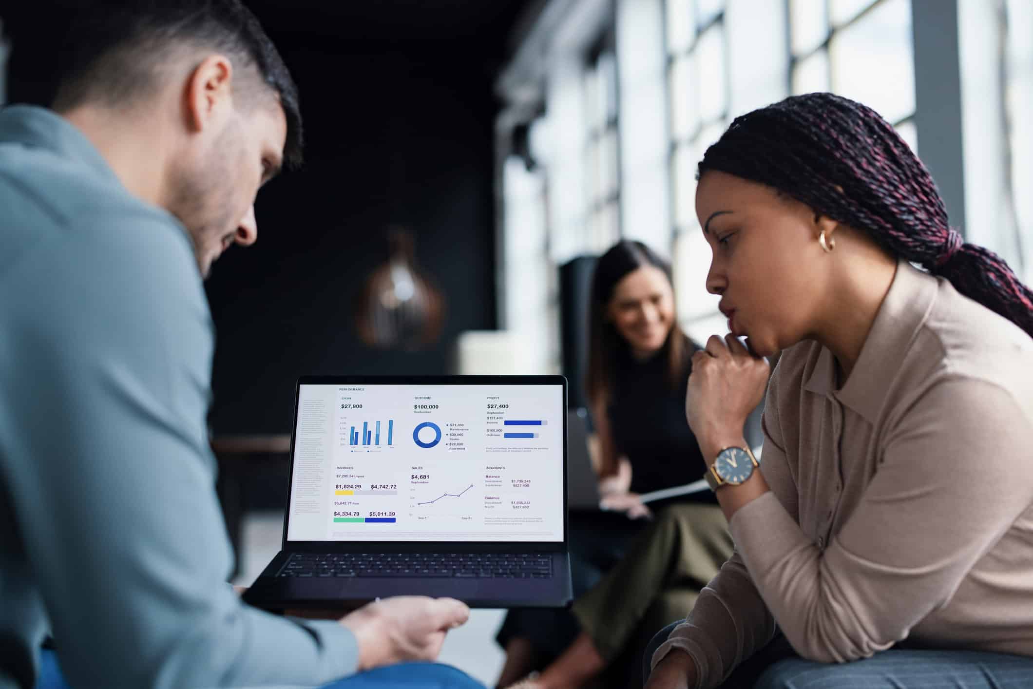 Two people review data charts on a laptop, focusing on resource optimization for law firms.