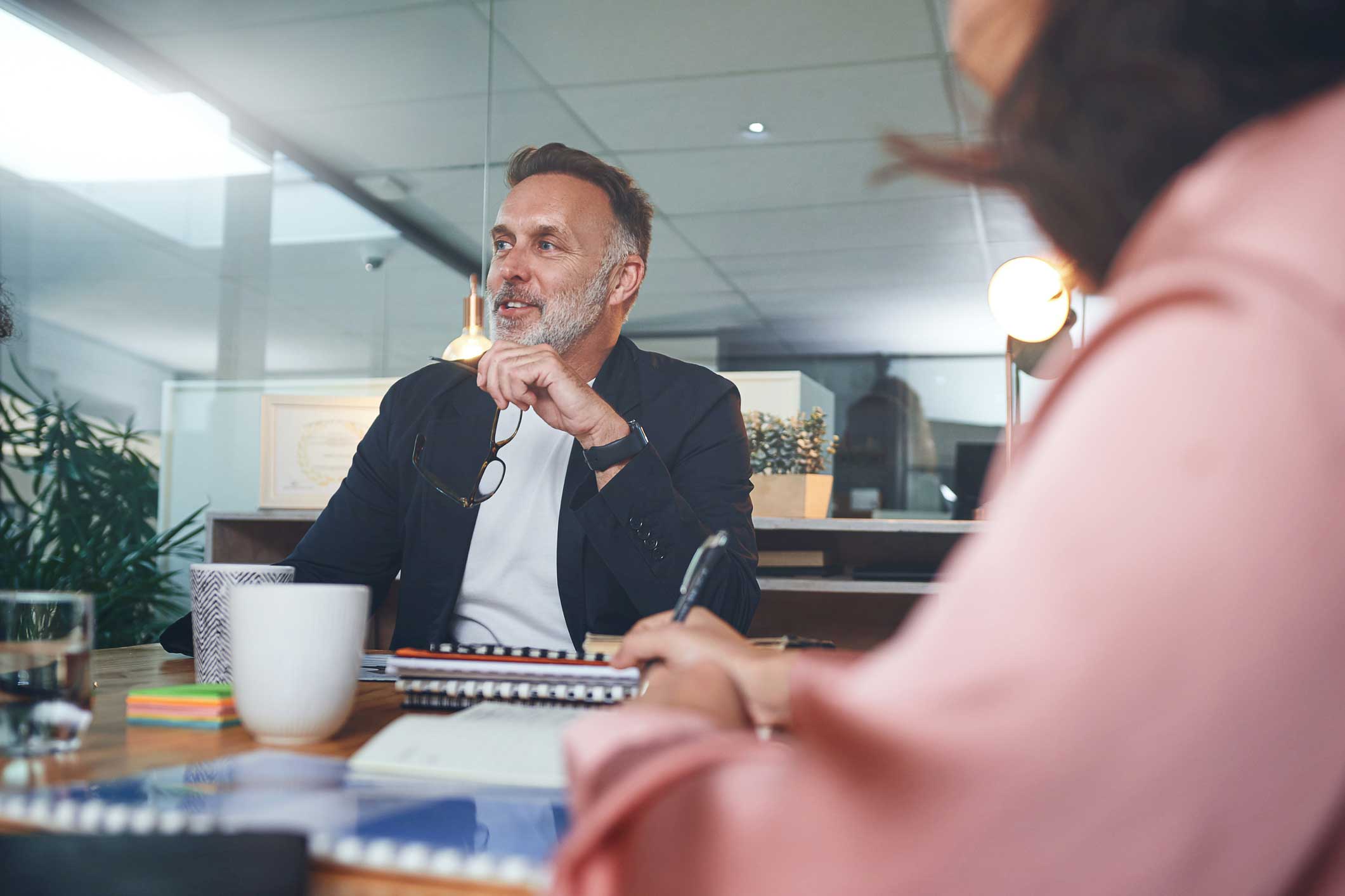Man in business meeting smiling, discussing Law Firm Financial Management Advisory at a desk.