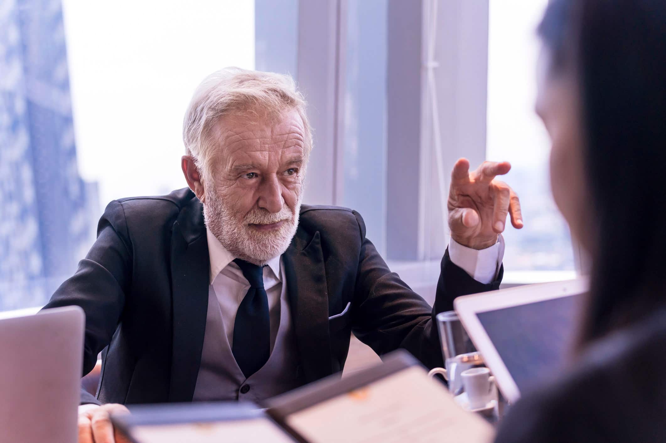 Elderly man in suit discusses Law Firm Marketing Consulting Services with a colleague in an office.