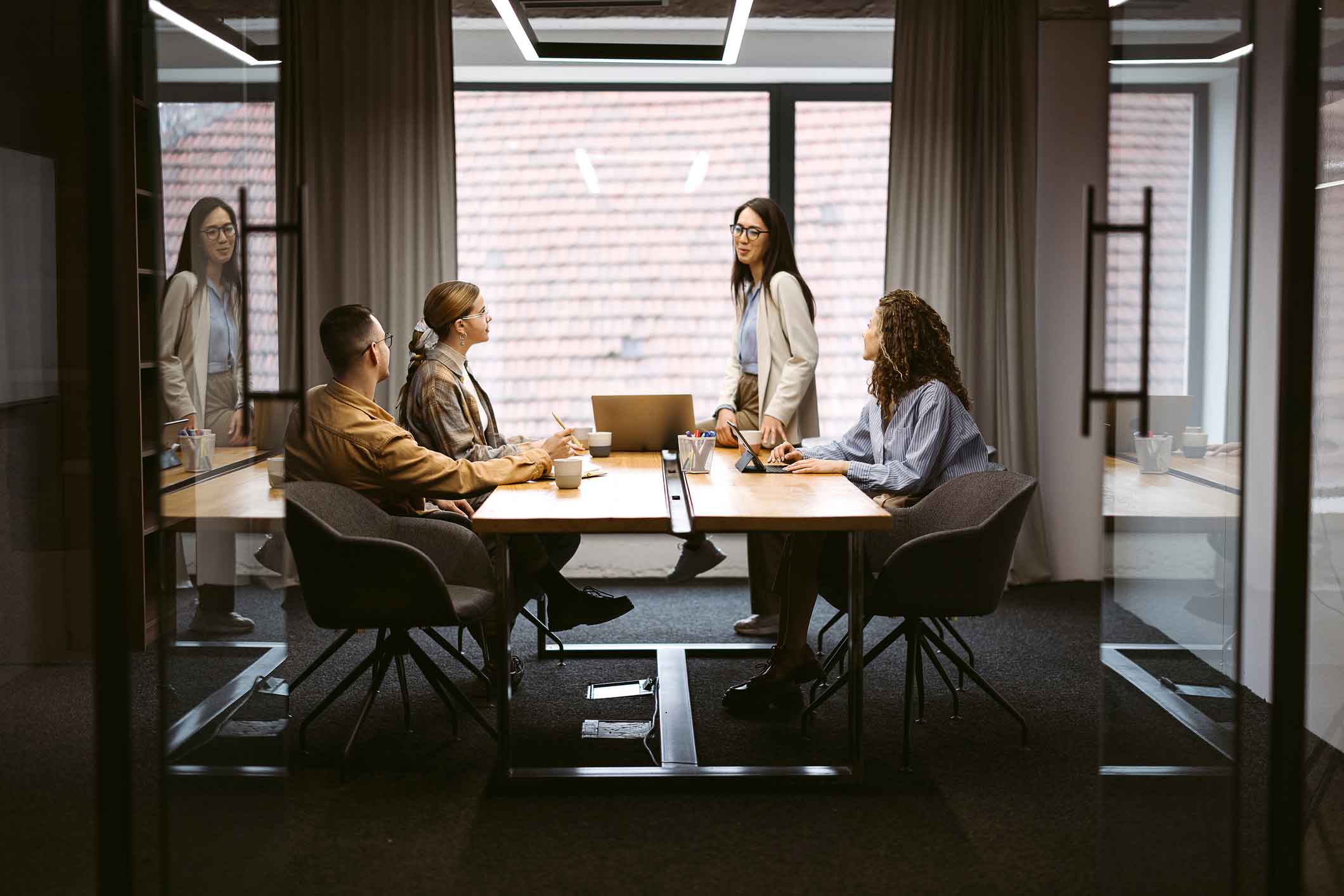 Four people, including IT disaster recovery consultants, meet in a modern office with large windows.