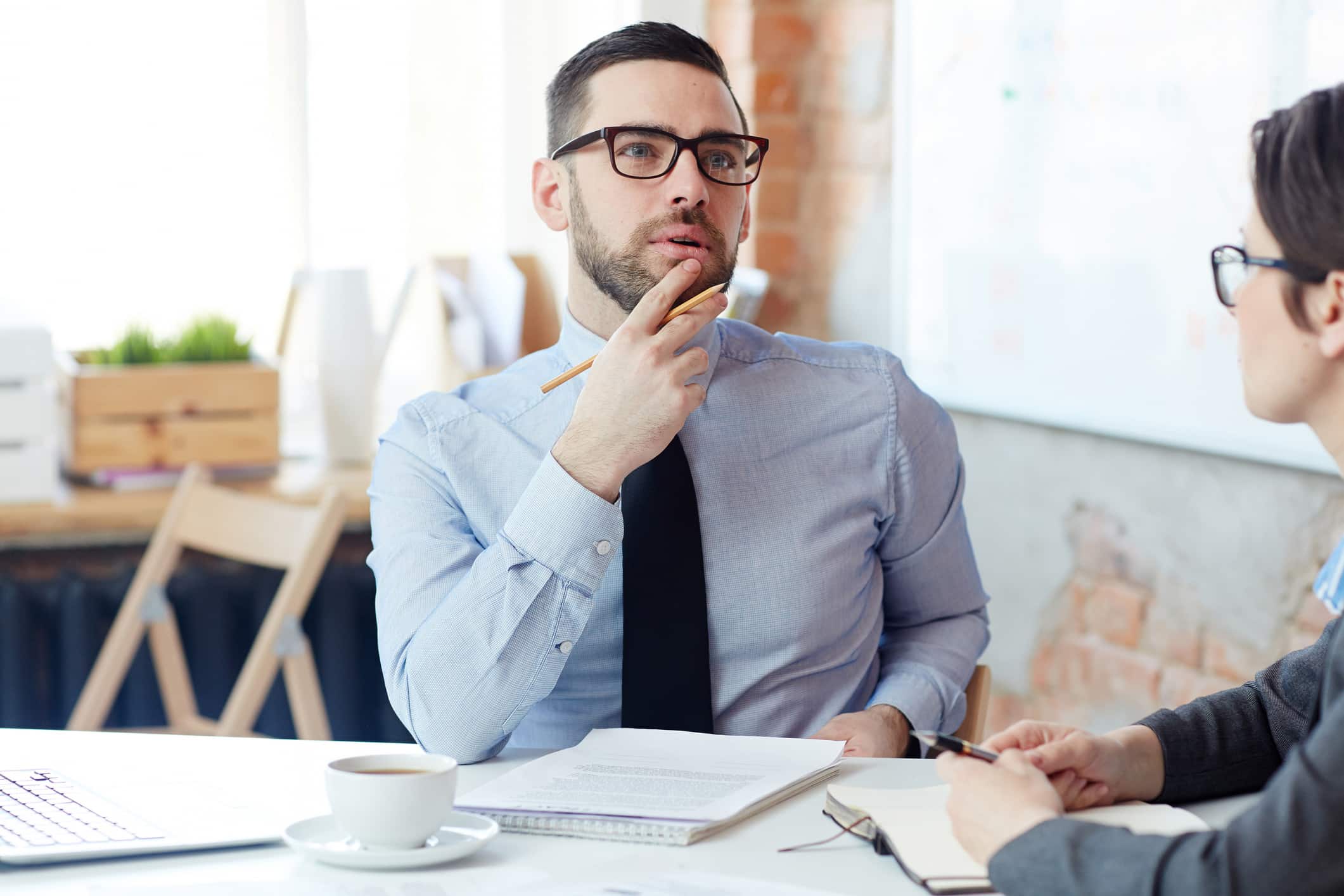 Man in glasses thinking during an eDiscovery document review at a consulting firm meeting.