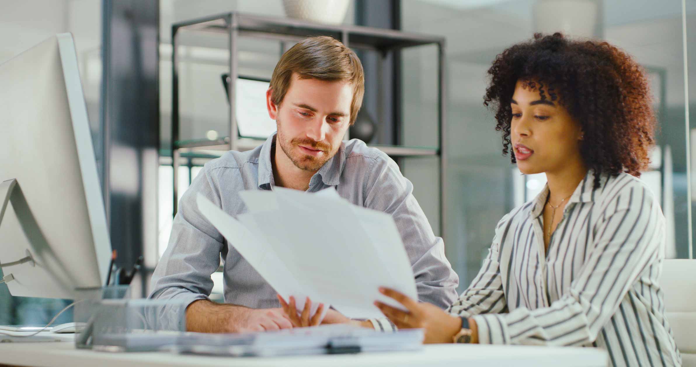Two colleagues review eDiscovery documents together at a desk in a modern office setting.