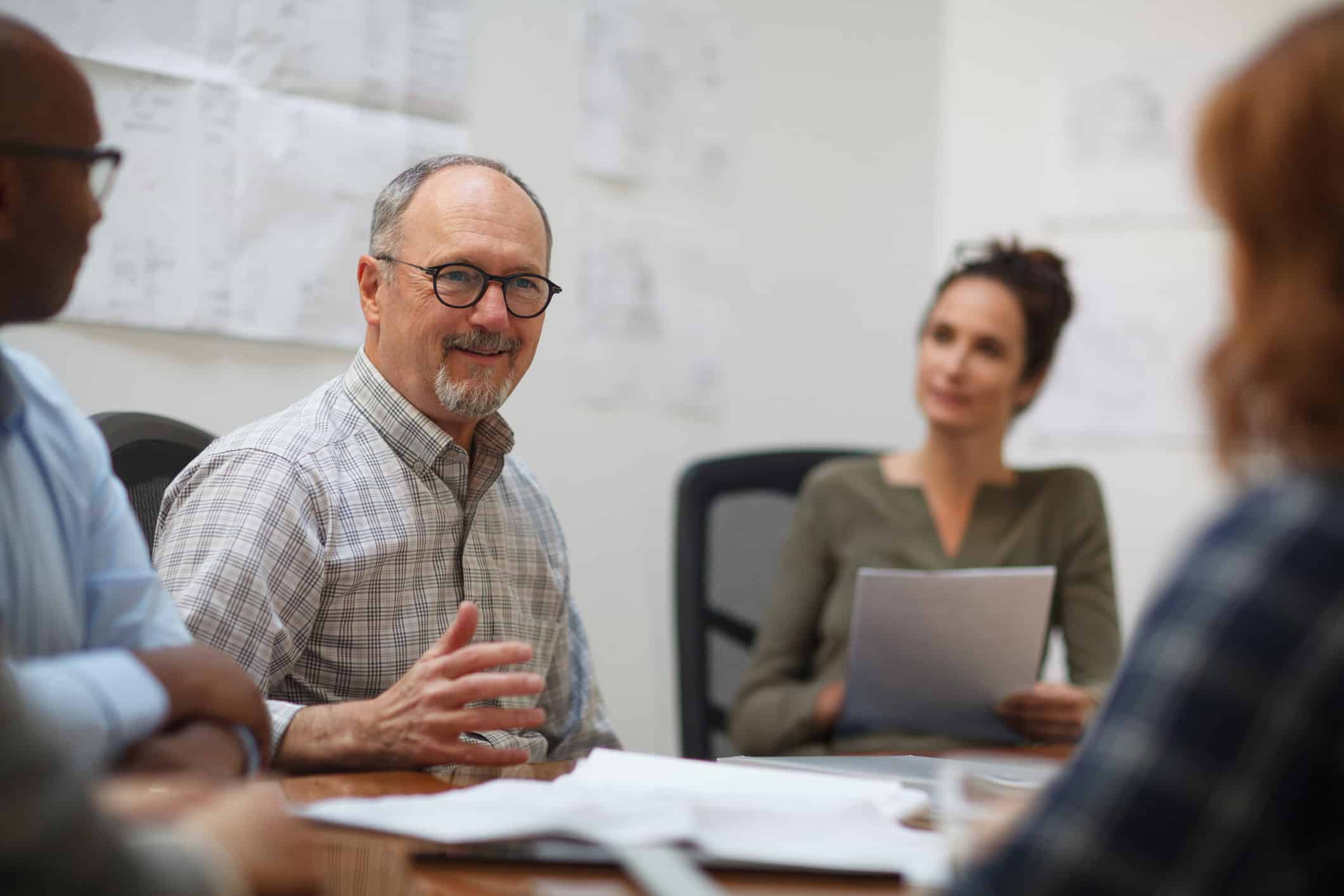Four people discussing change management execution around a table in an office setting.