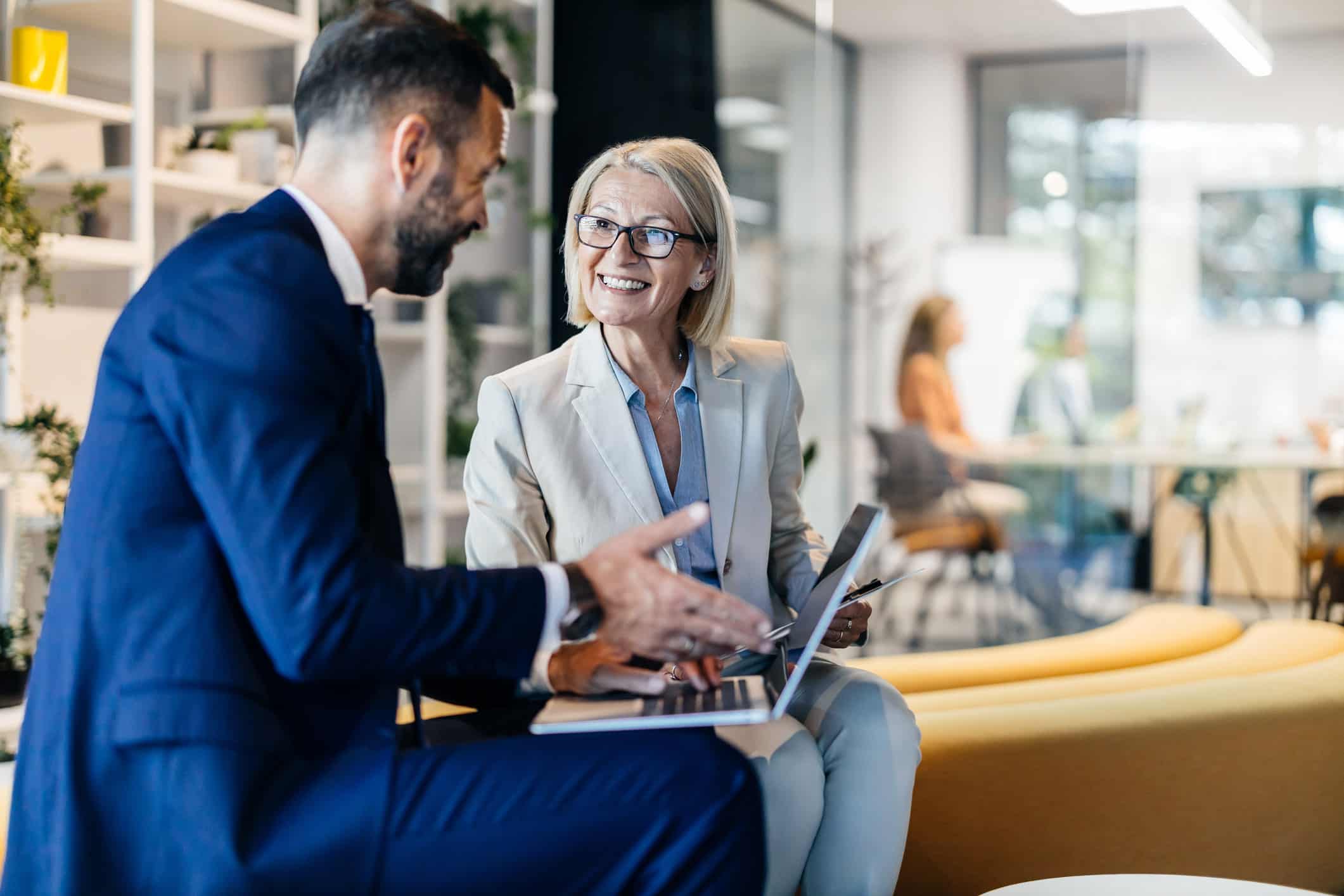 Two businesspeople discussing market intelligence and target screening in a modern office.