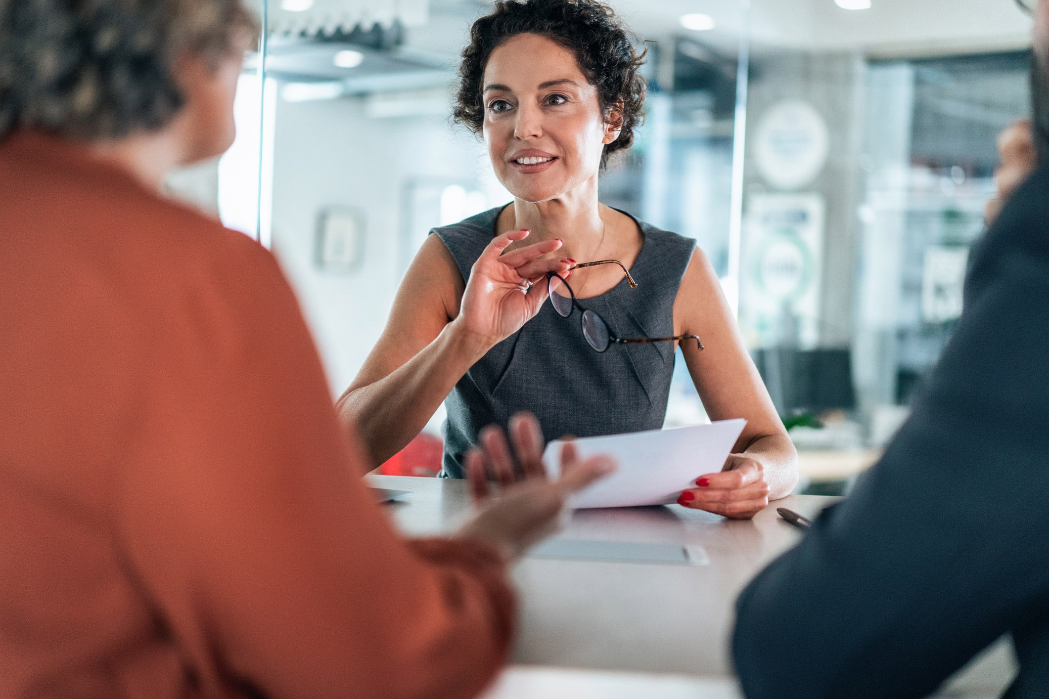 Woman in a business meeting discussing Market Opportunity Mapping with colleagues at a table.