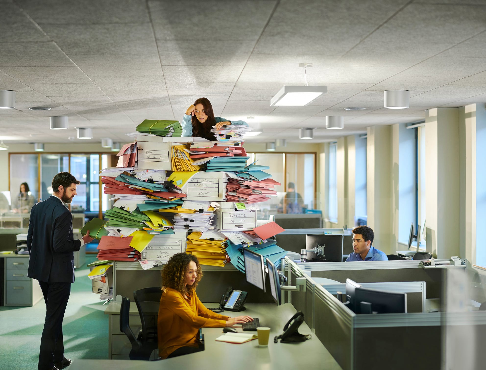 Woman overwhelmed by eDiscovery document review process in a busy office with coworkers nearby.