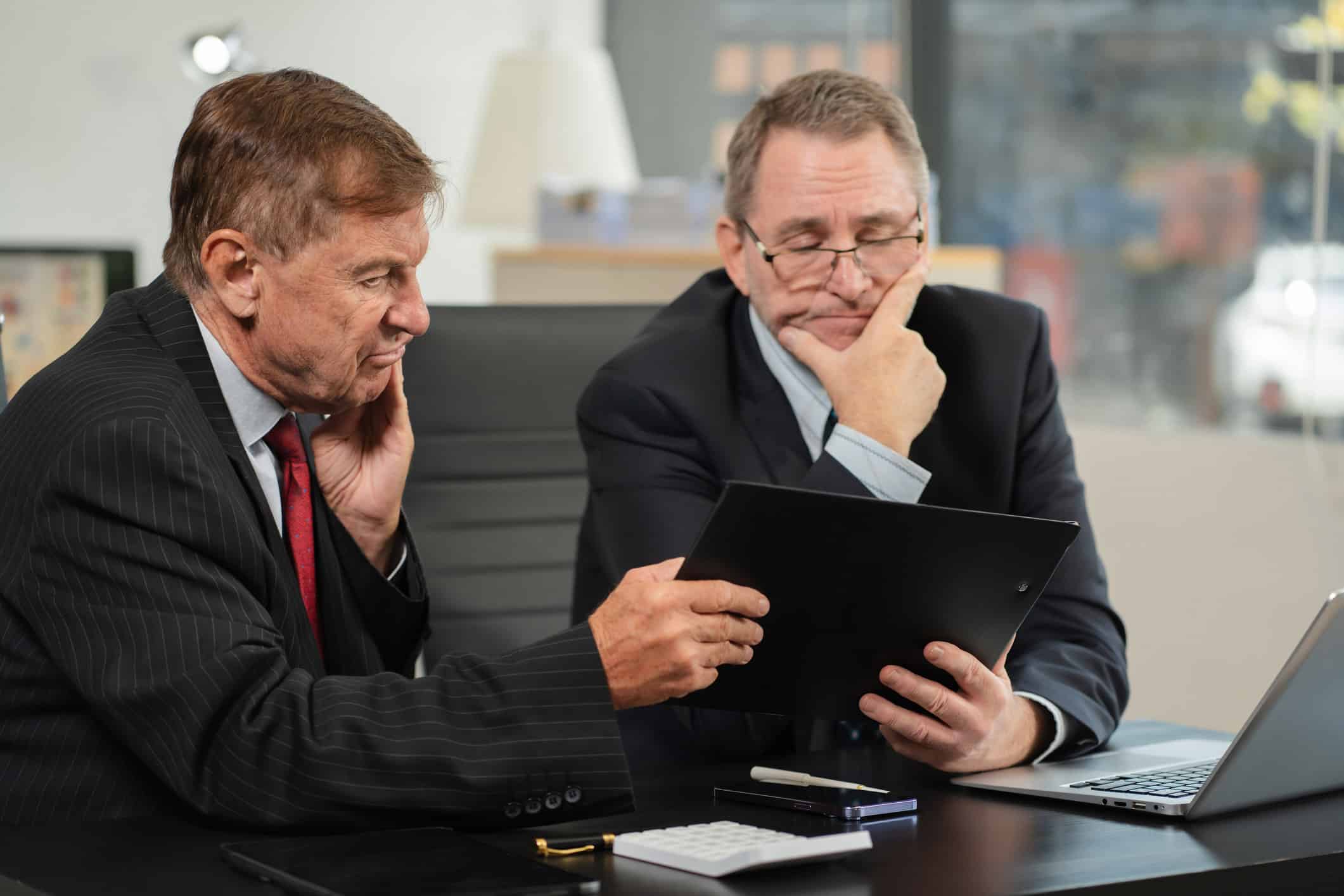 Two men in suits review a document—experts in law firms resource optimization consulting.