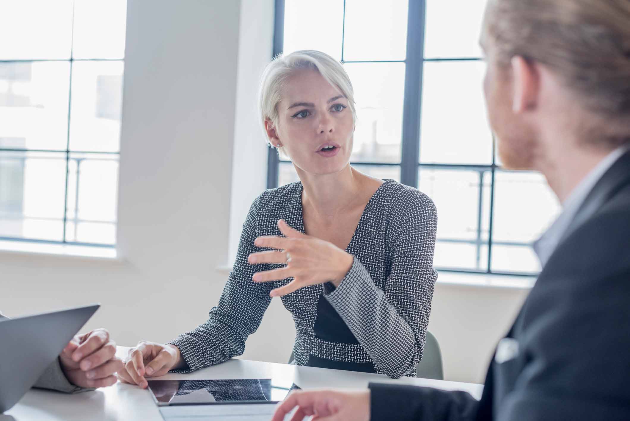 Businesswoman discusses Digital Forensics Consulting Services with a colleague at a meeting table.