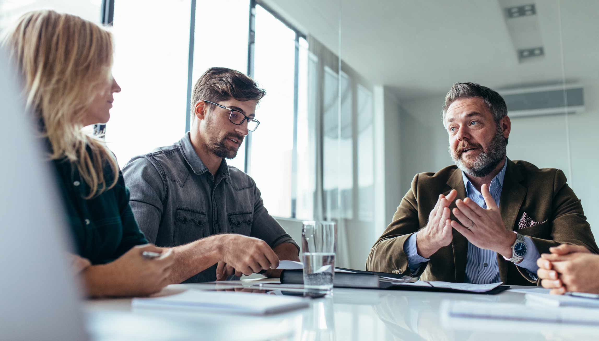 Group discussing Machine Learning Advisory around a table in a modern office setting.
