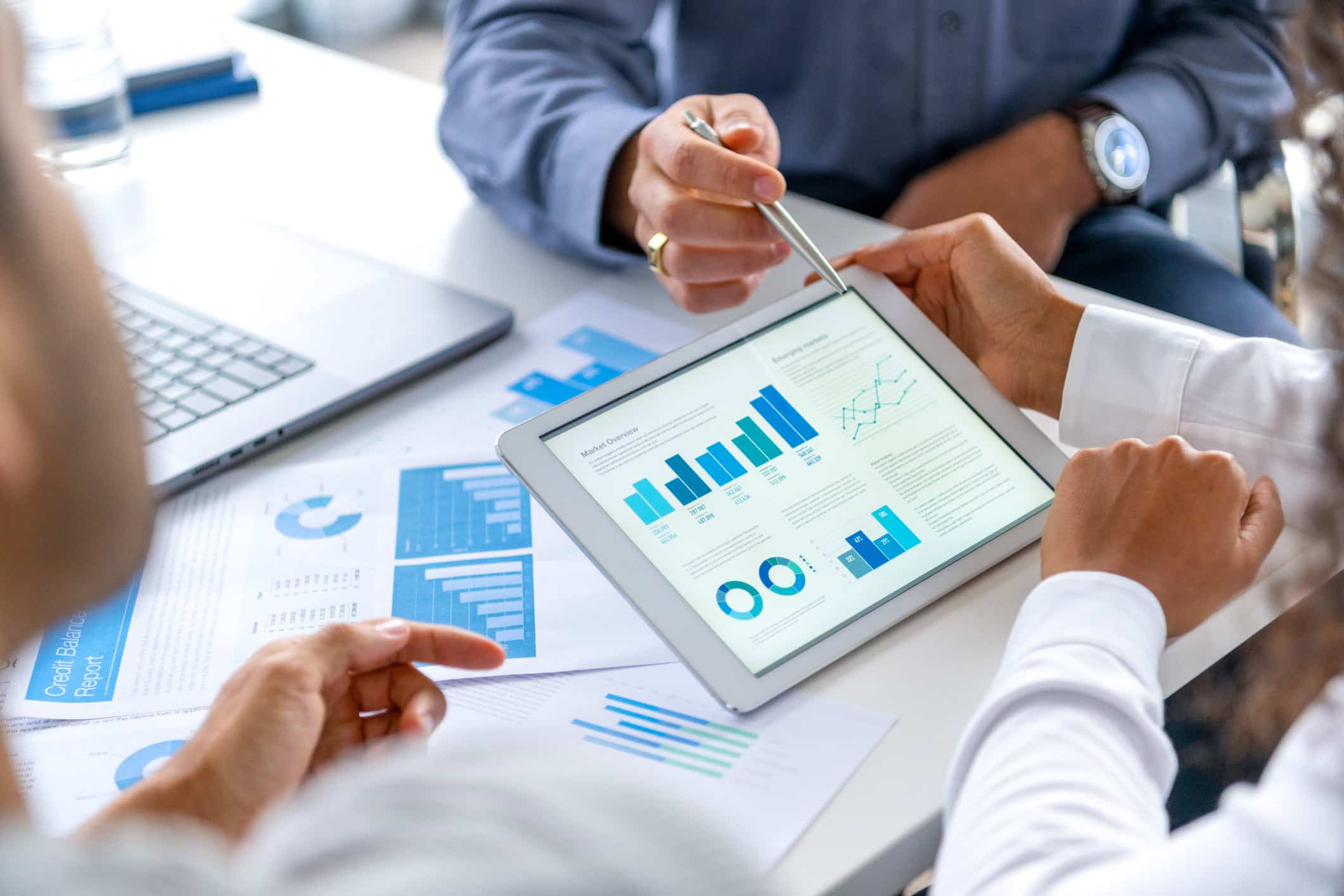Three people review charts and reports, focusing on law firm financial efficiency at a desk.