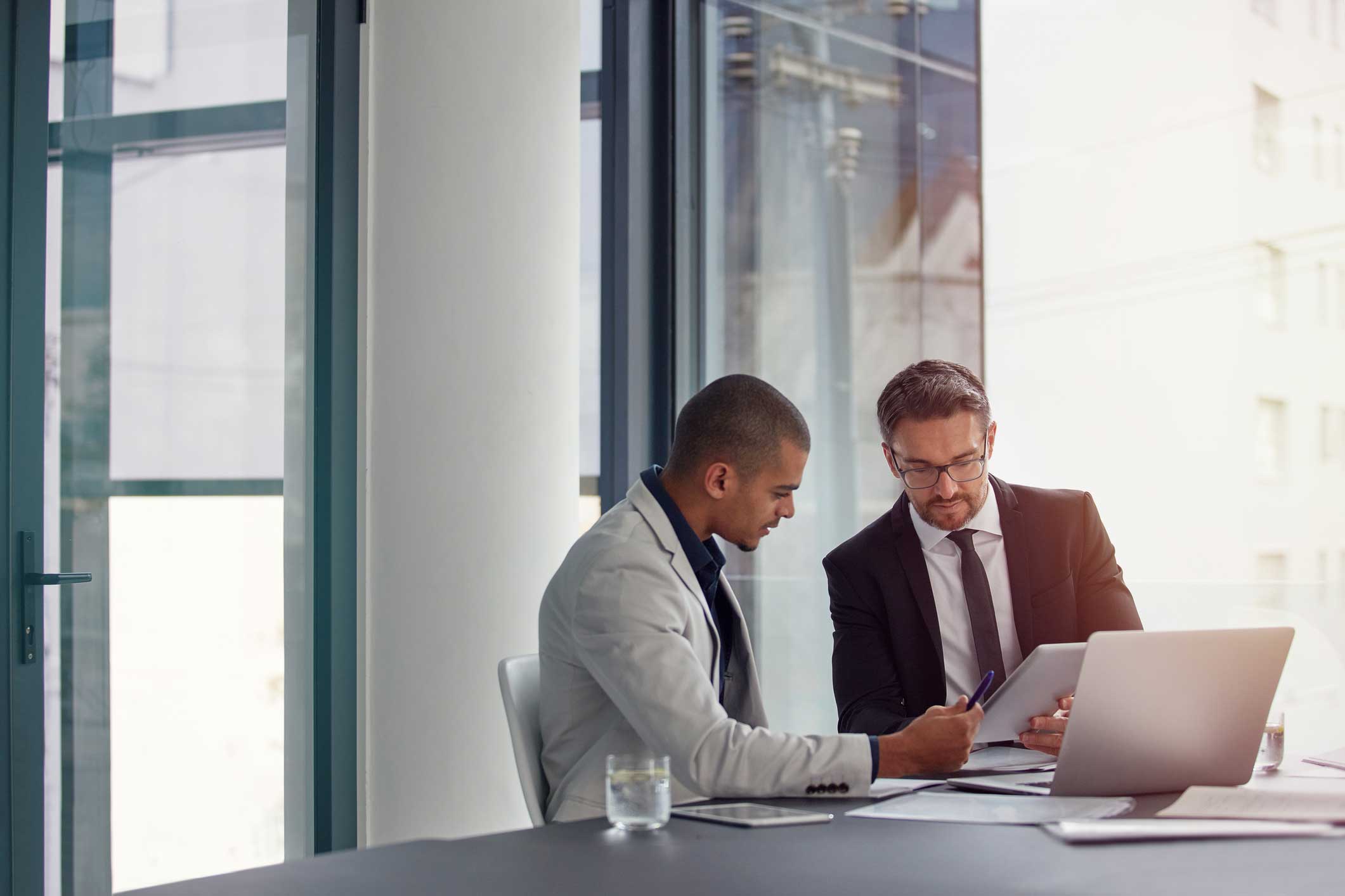 Two cybersecurity consultants in an office reviewing documents together at a desk.