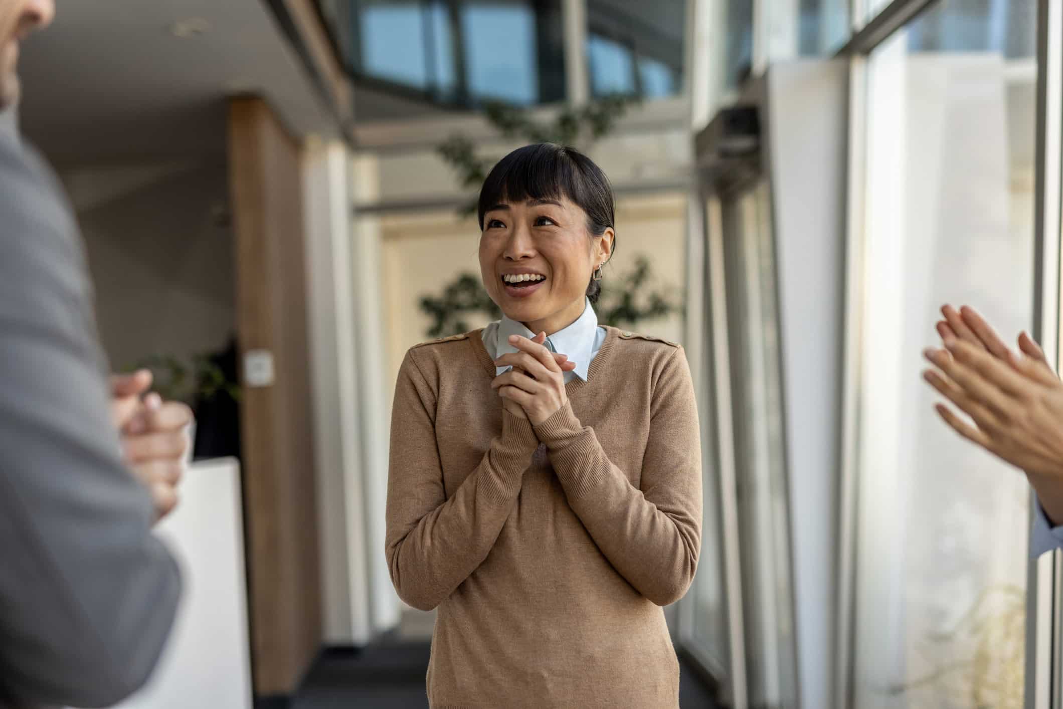 Smiling woman clasping hands, celebrated for her workforce development enablement efforts.