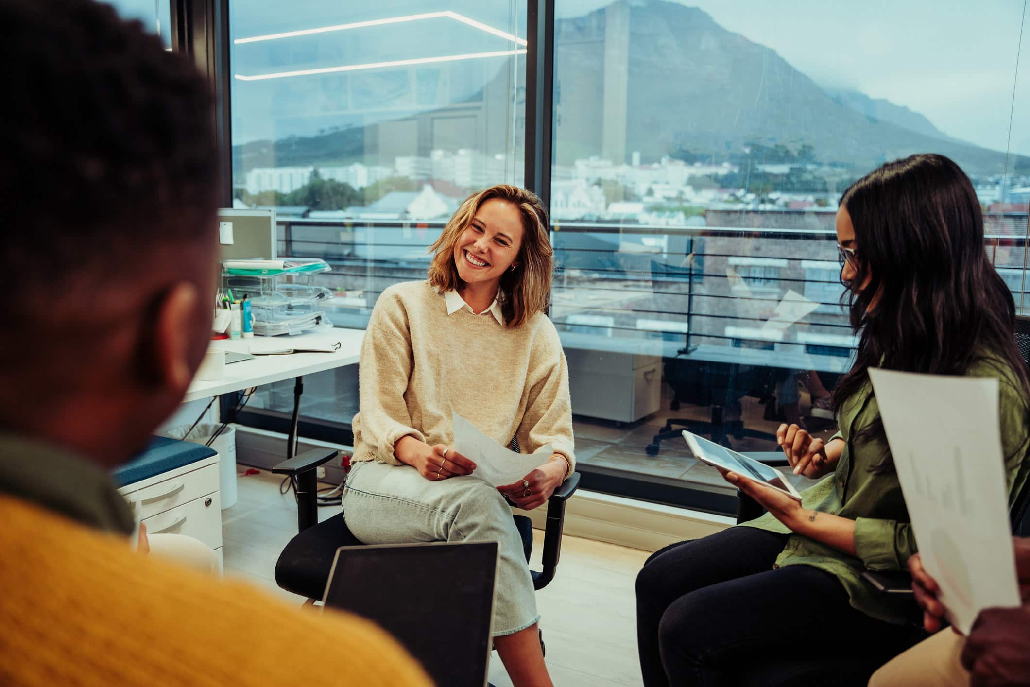Three people discuss Law Firm Operations Management in a bright office with mountain views.