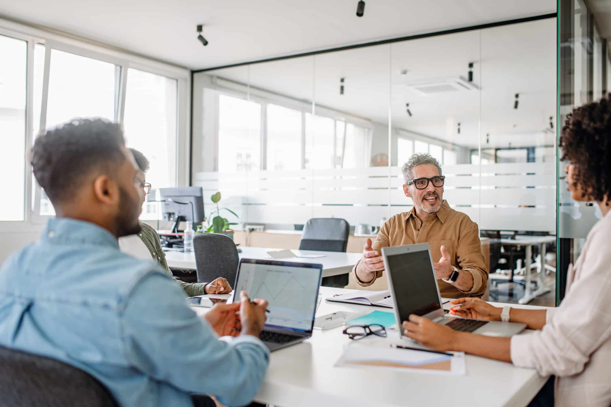 Four people discuss eDiscovery data management around a table in a modern meeting room.
