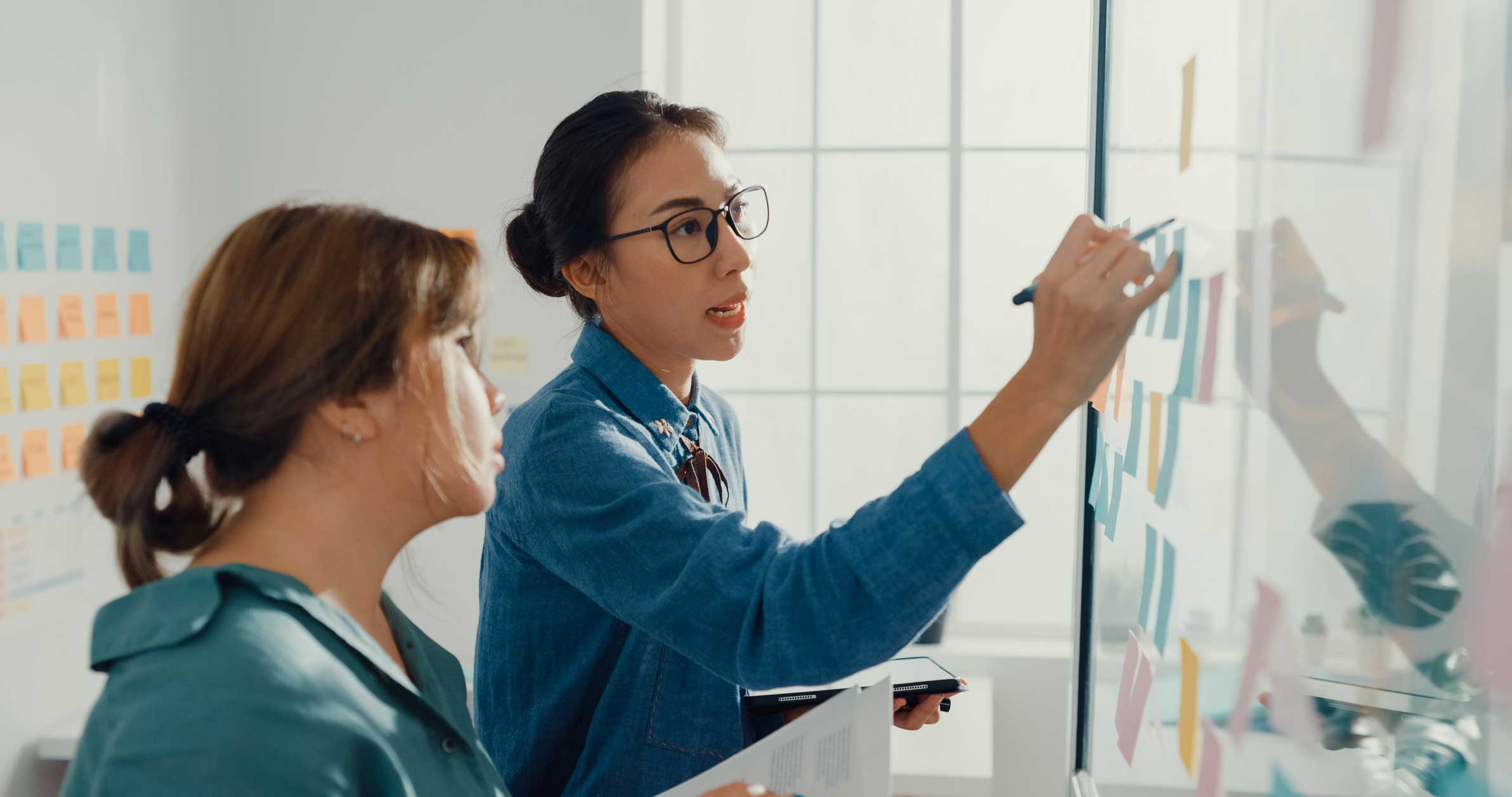 Two women brainstorming CAL Integration on sticky notes during a meeting.