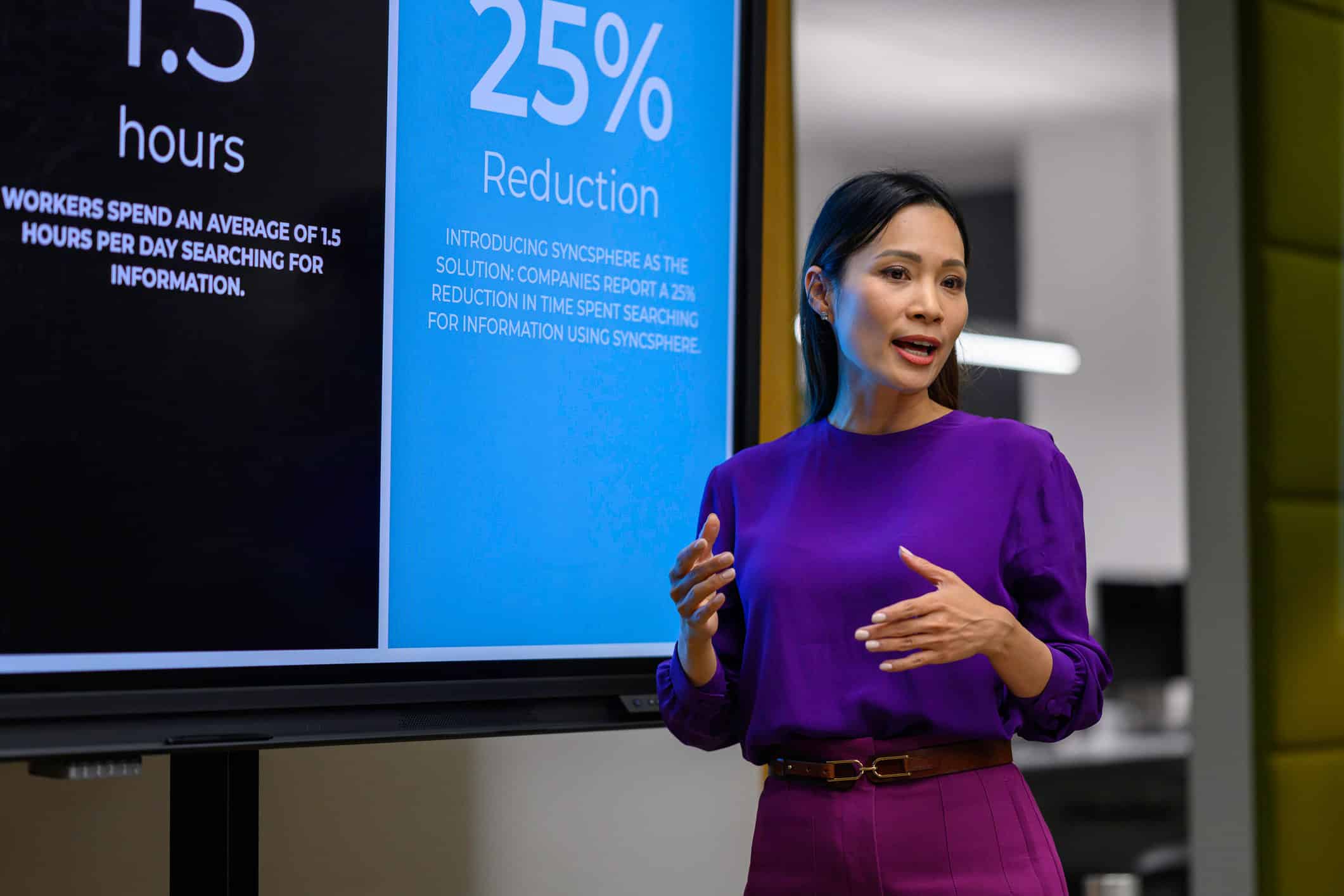 Woman in purple presents data on M&A Integration Execution and search time reduction on screen.