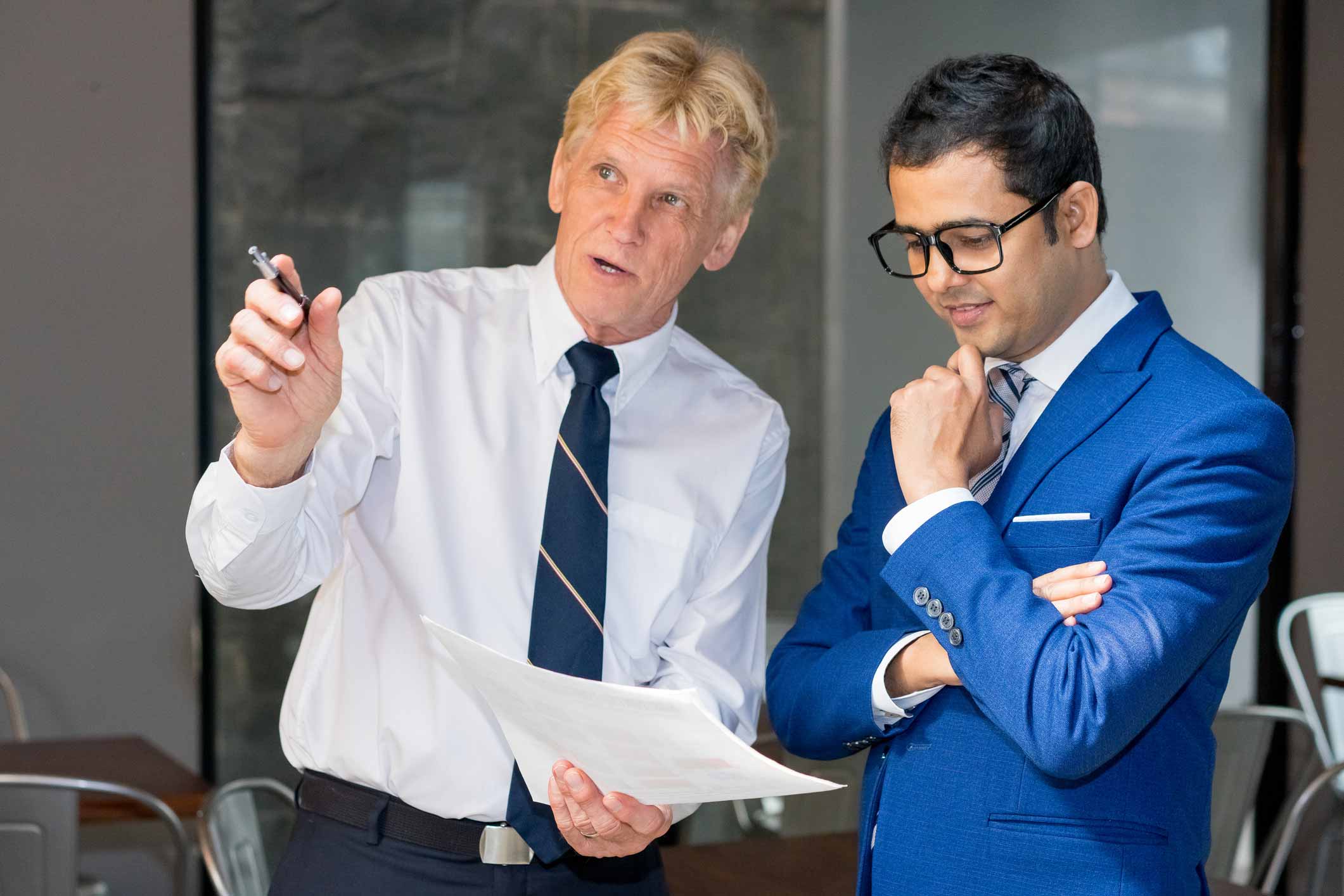 Two businessmen discuss Law Firm Financial Management Consulting over a document thoughtfully.