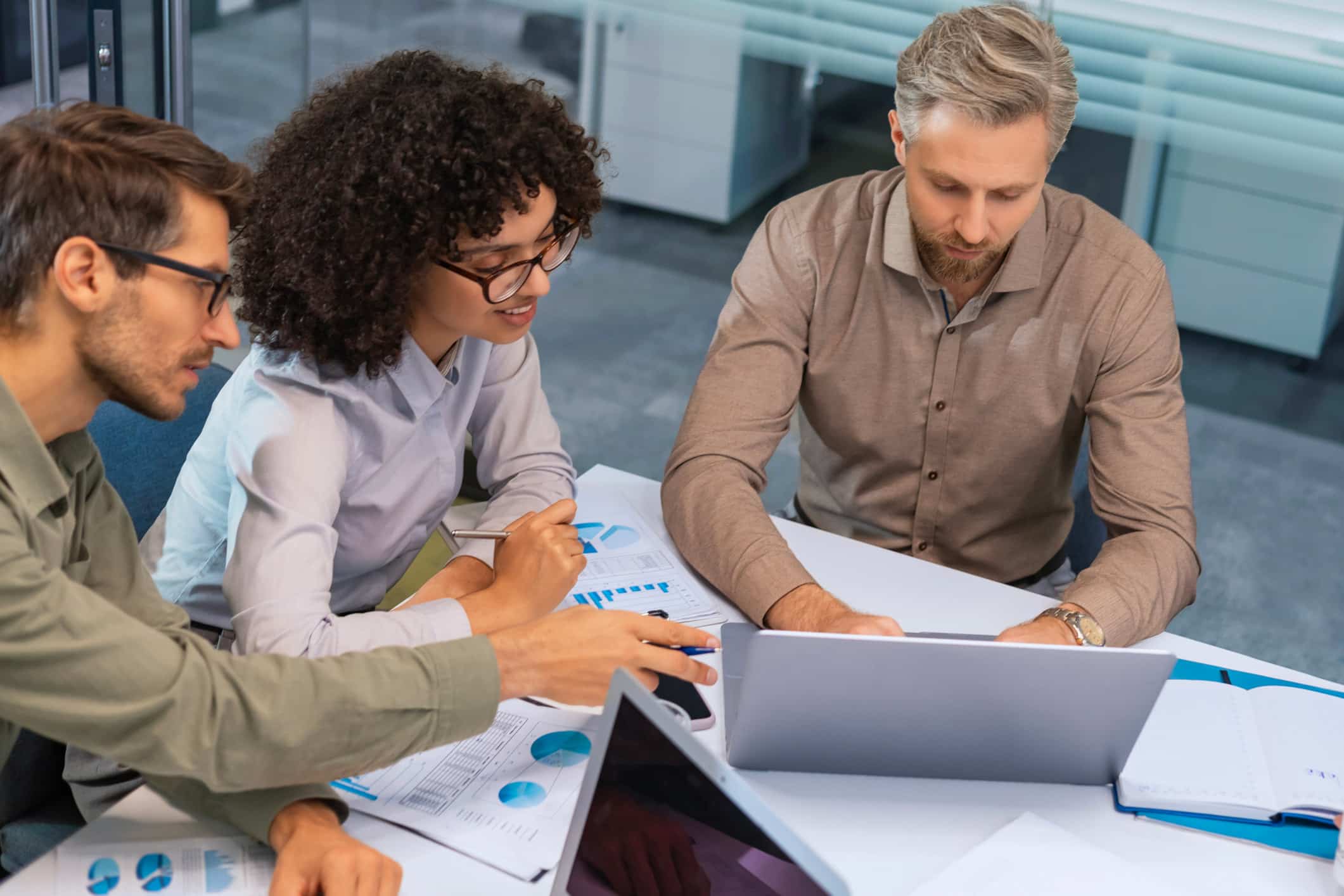 Three people discuss Law Firm BPM Mapping with charts and graphs at a table with a laptop.